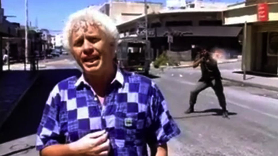 A Norwegian reporter broadcasts despite gunfire around him.