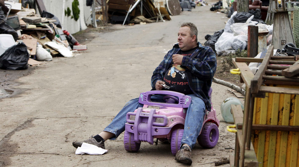 Volodymyr Krupa takes a cigarette break on his street while cleaning out his flood damaged home in the Staten Island. (AAP)