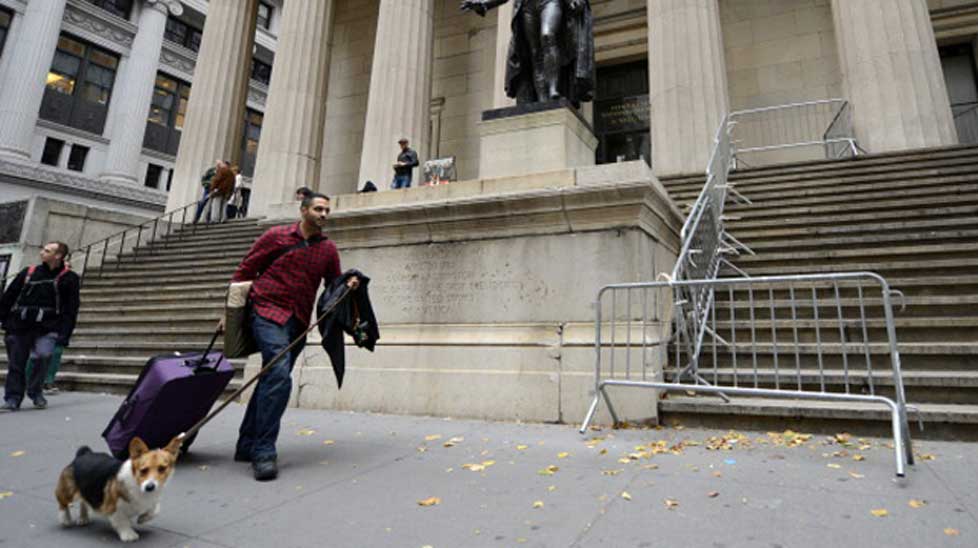 Kabir Bindra walks up Wall Street with his luggage and dog near the New York Stock Exchange. 
