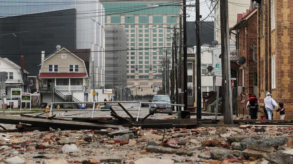 People walk past debris where a section of boardwalk was destroyed.