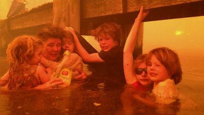 Tammy Holmes and grandchildren Charlotte, Esther, Liam, Matilda and Caleb cling to the jetty to flee the fires raging around them.
