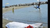 Italian beachgoers play ball games and sunbake next to a body in Formia.