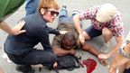 Bystanders help a bleeding shooting victim while waiting for paramedics. (AAP) 