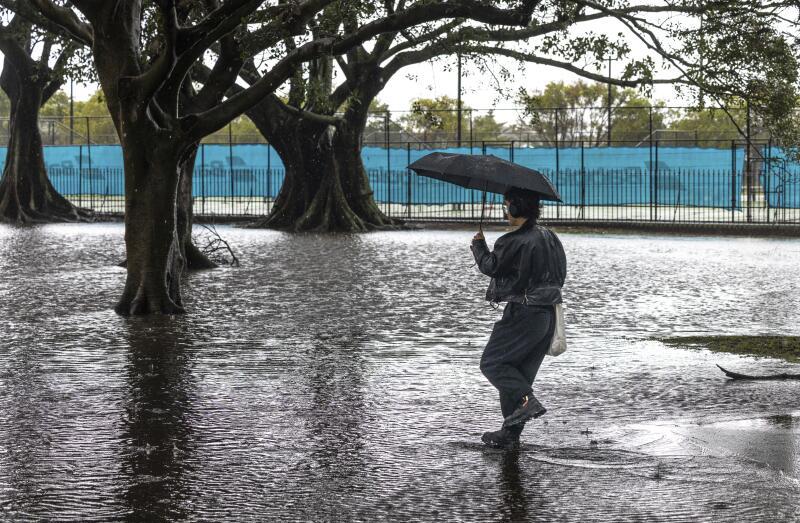 Um pedestre distraído entra no Federation Place inundado em Moore Park na quinta-feira, 11 de setembro de 2025.