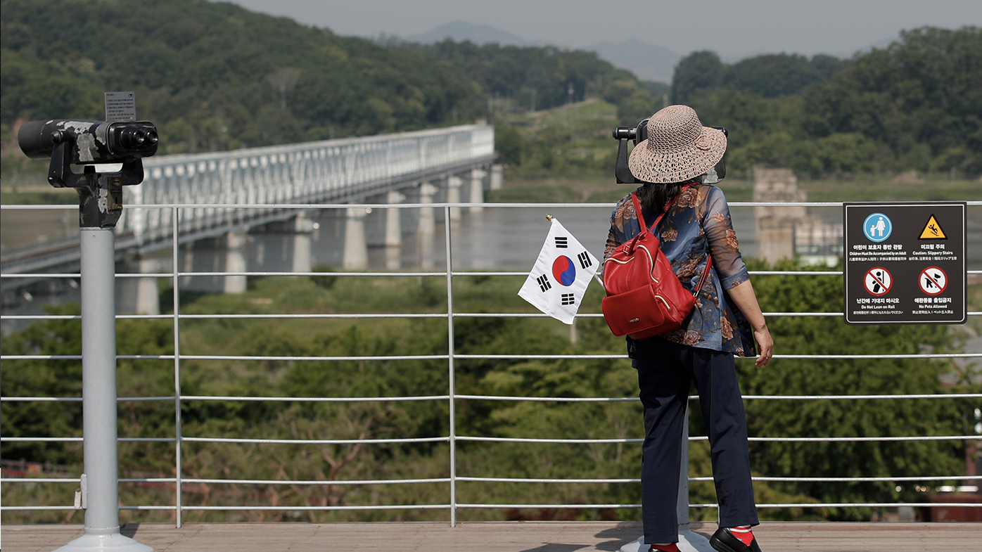 A visitor carrying a national flag uses binoculars to view the northern side at the Imjingak Pavilion in Paju, South Korea, Tuesday, June 9, 2020. North Korea said Tuesday it will cut off all communication channels with South Korea as it escalates its pressure on the South for failing to stop activists from floating anti-Pyongyang leaflets across their tense border. (AP Photo/Lee Jin-man)