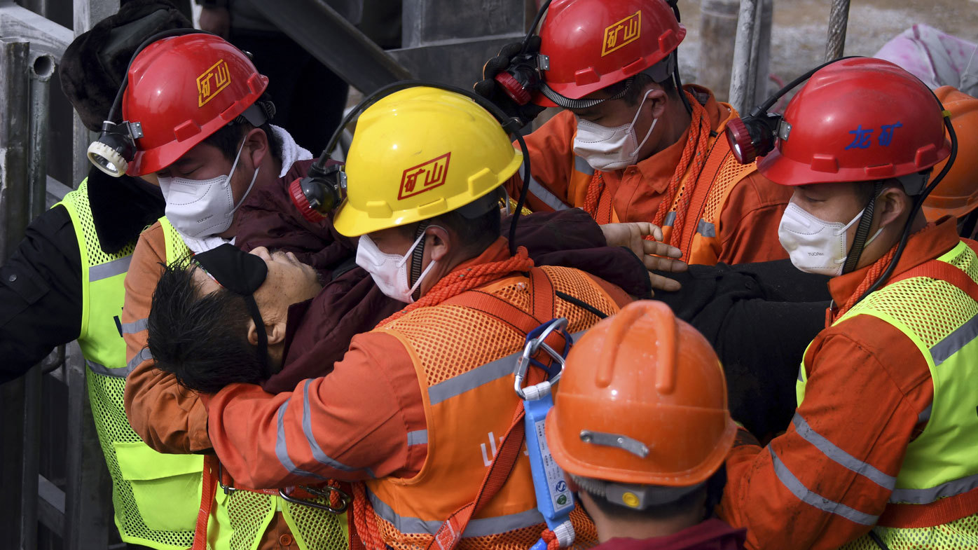 In this photo released by Xinhua News Agency, rescuers carry a miner who was trapped in a mine to an ambulance in Qixia City in east China's Shandong Province.