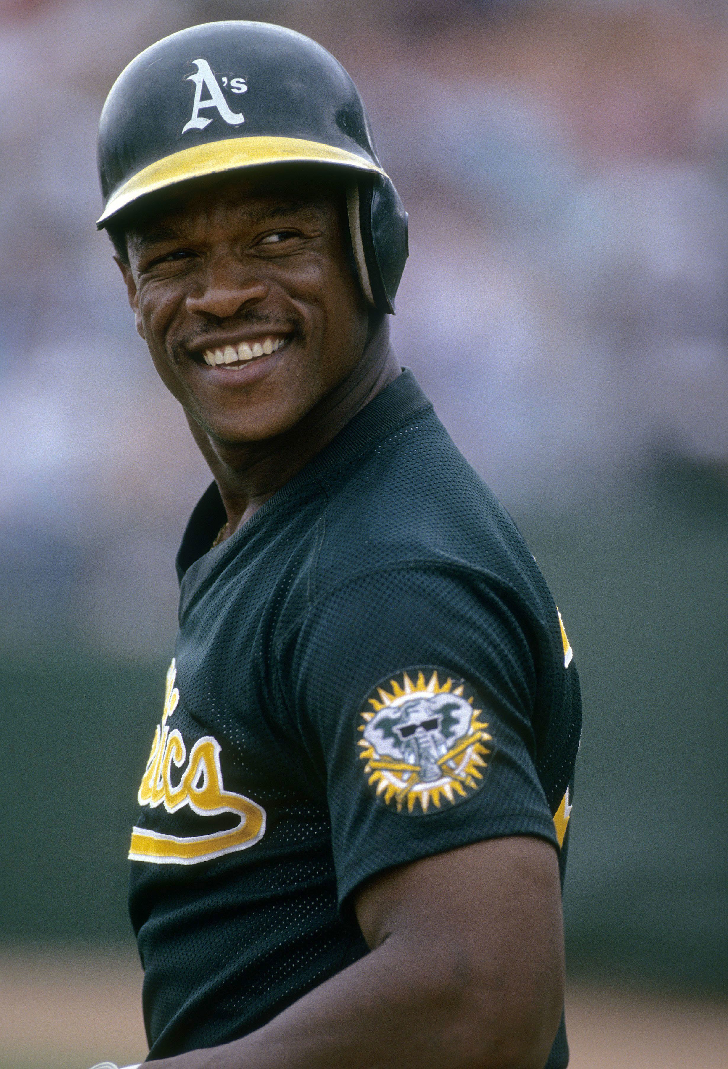 El jardinero Rickey Henderson de los Atléticos de Oakland en el campo sonriendo durante un juego en el Oakland Coliseum en Oakland, California