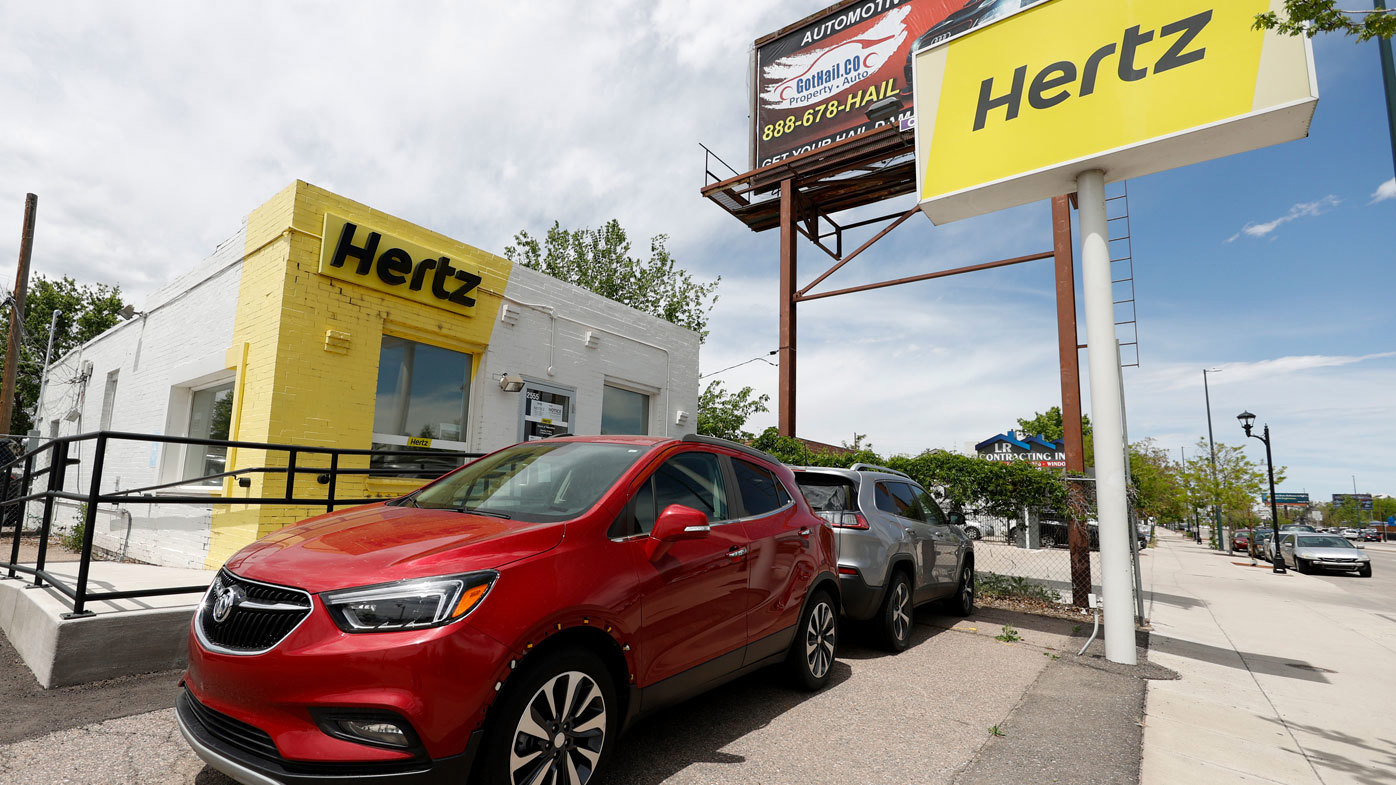 Vehículos de alquiler estacionados afuera de una oficina cerrada de alquiler de autos de Hertz en Denver.