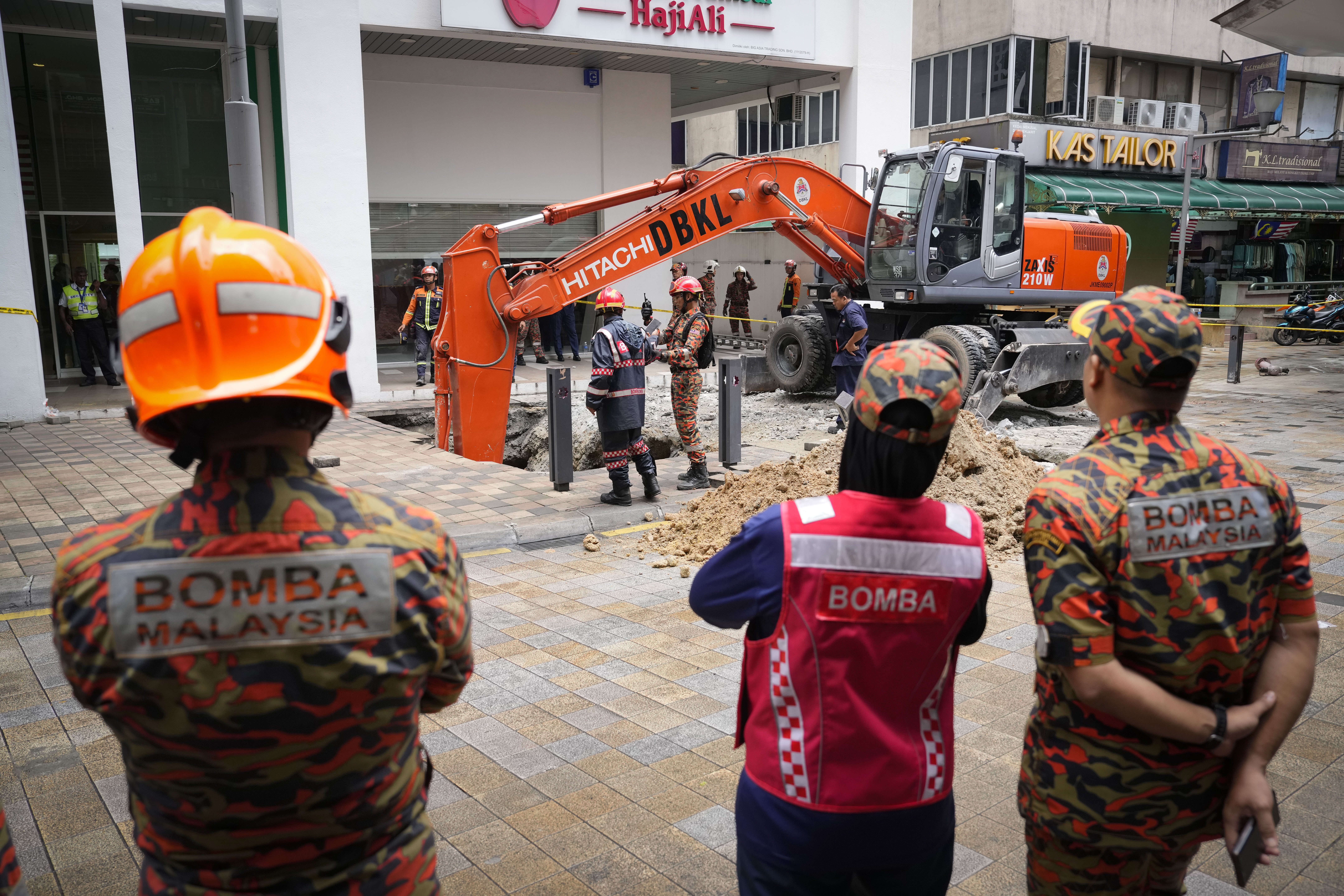 Fire and Rescue department checking on after receiving reports that a woman has fallen into the sinkhole after a section of the sidewalk caved in Kuala Lumpur, Friday, Aug. 23, 2024. 