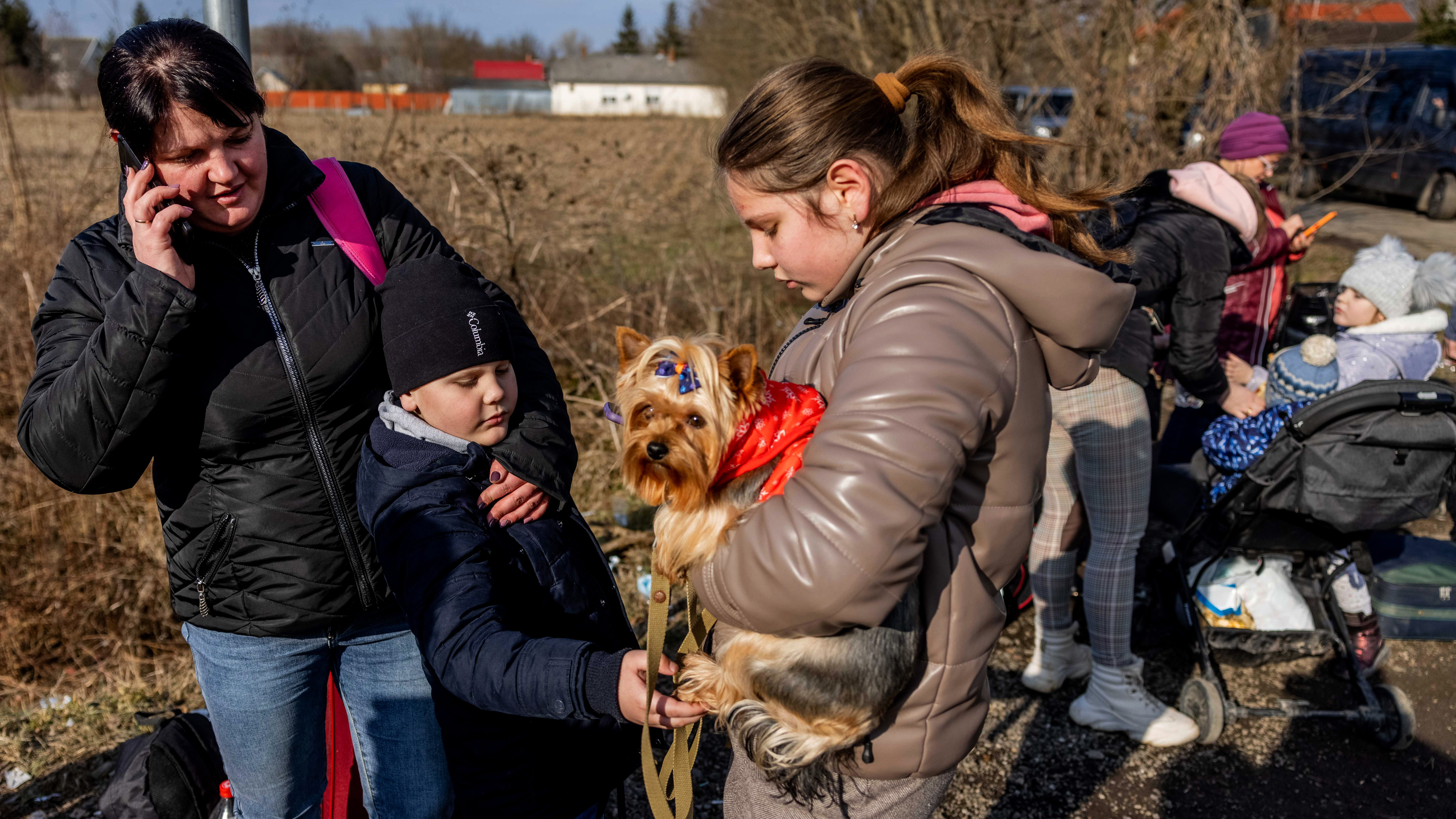 People wait with their belongings at the Tiszabecs-Tiszaujlak border crossing in Tiszabecs, Hungary.