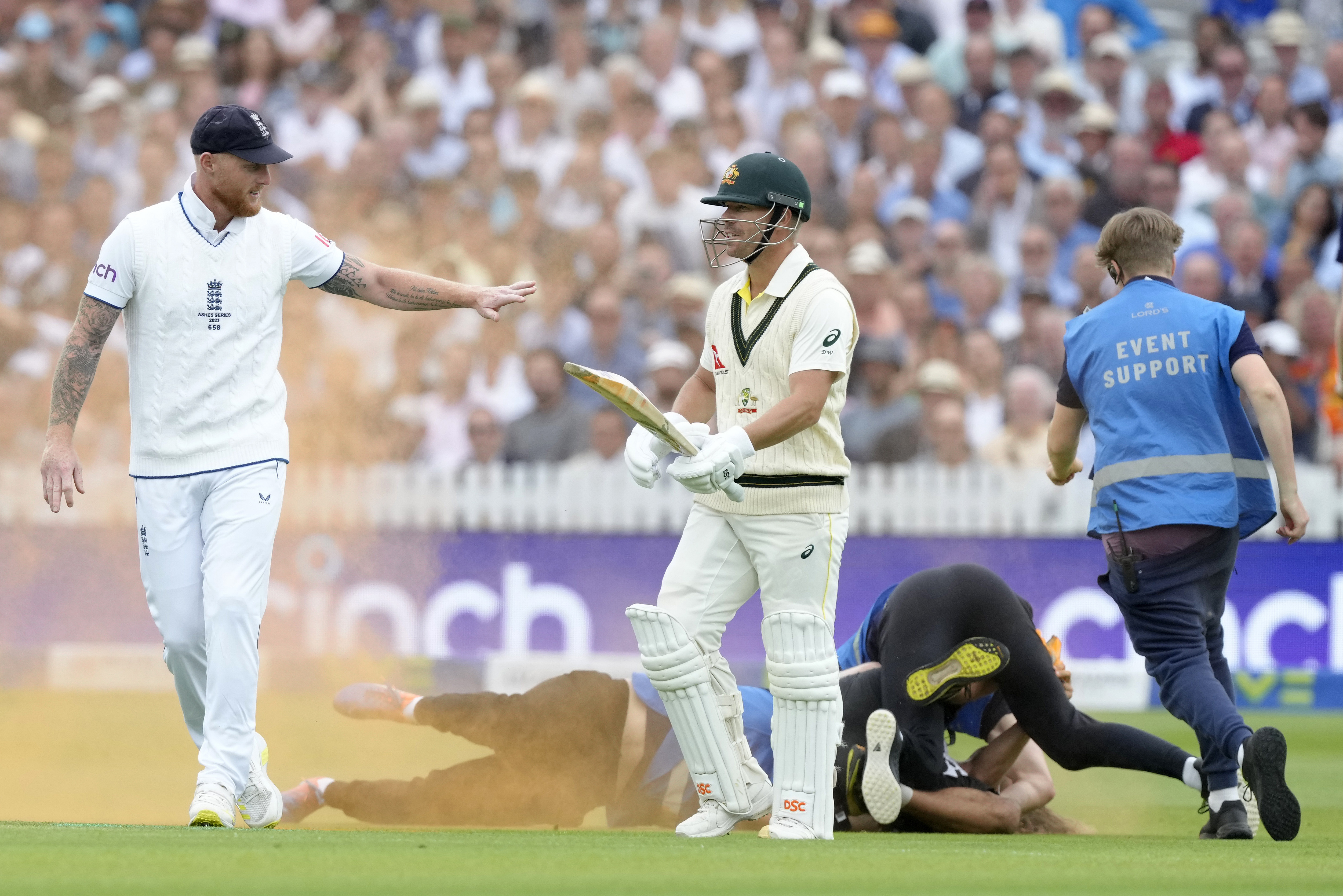 England's Ben Stokes (left) and Australia's David Warner react as a Just Stop Oil protester is apprehended after they threw colored powder on the pitch during day one of the second Ashes Test at Lord's.