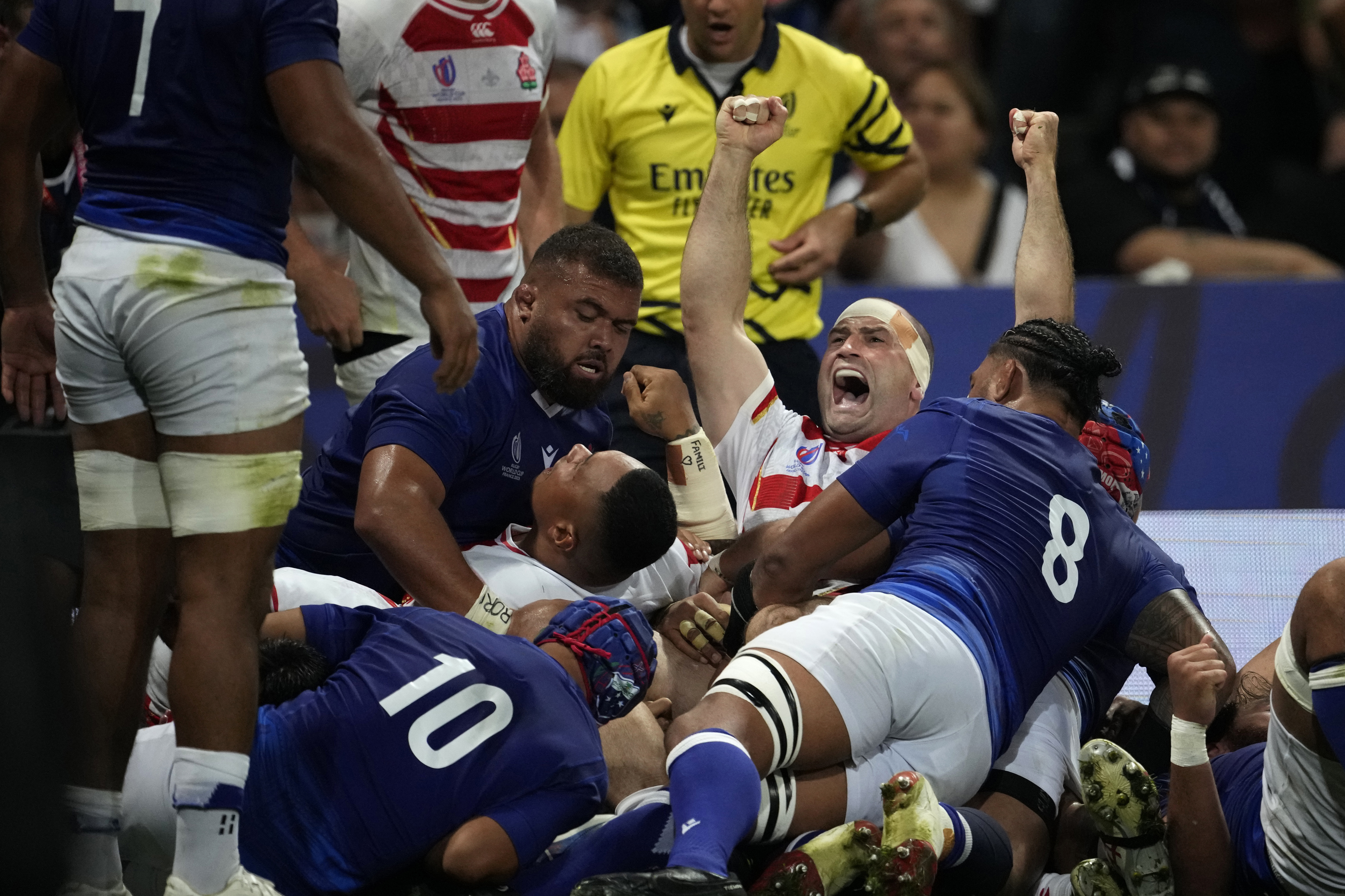 Japan's Craig Millar, centre, celebrates after his captain Kazuki Himeno scores a try during in their match against Samoa.