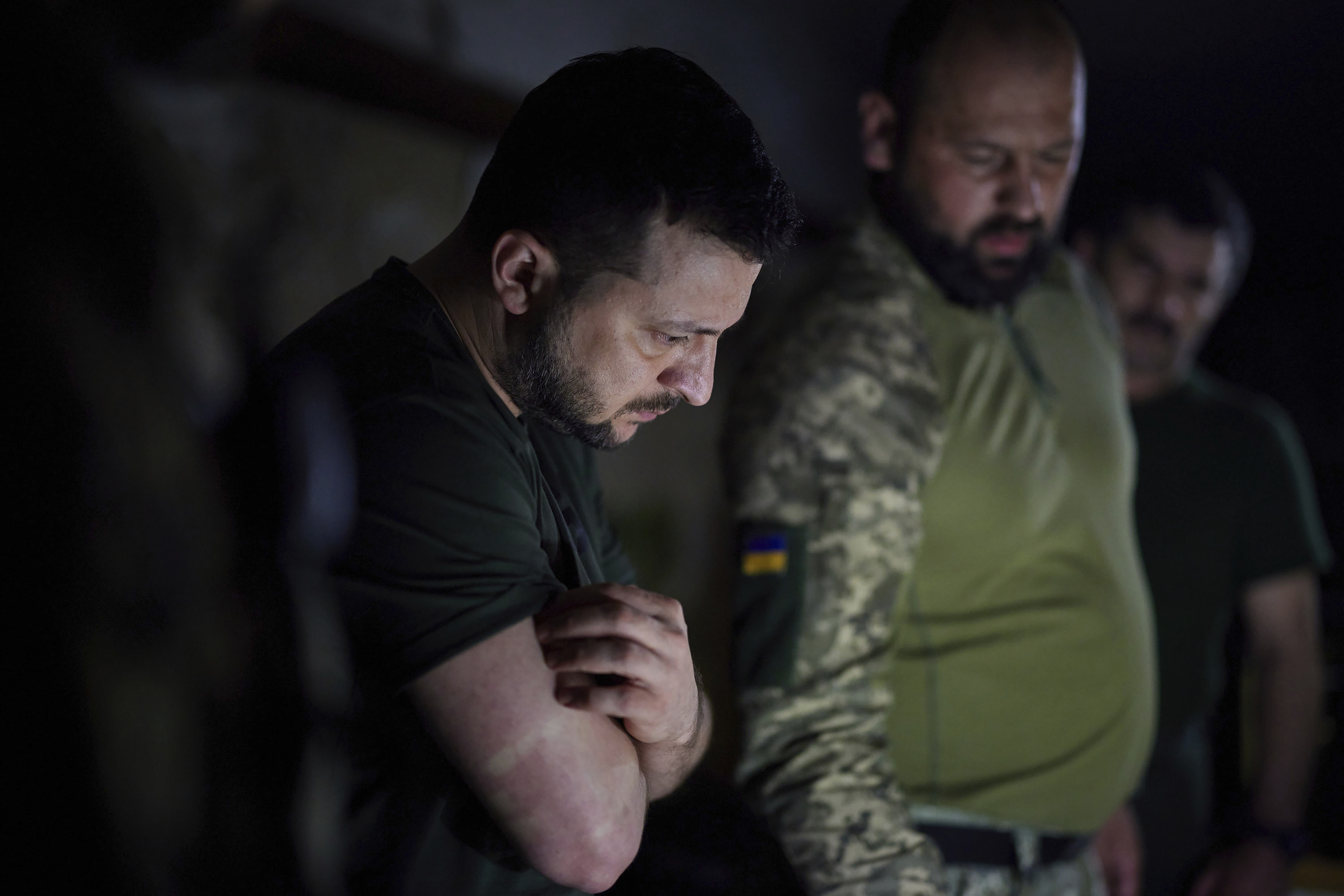 In this photo provided by the Ukrainian Presidential Press Office, Ukrainian President Volodymyr Zelenskyy, left, listens to a servicemen report close to the front line in Donetsk region, Ukraine, Sunday, June 5, 2022. (Ukrainian Presidential Press Office via AP)