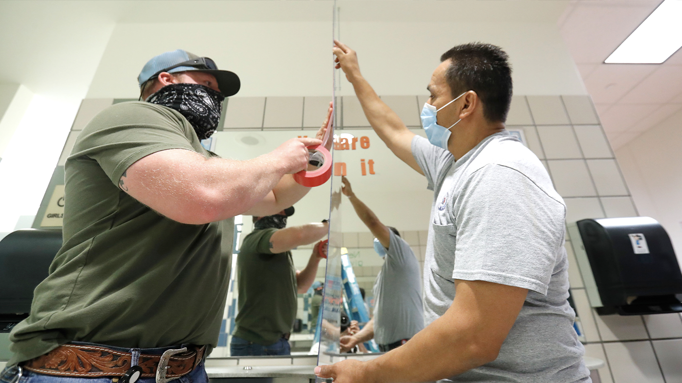 Wearing mask amid the concern of COVID-19, Richardson Independent School District workers Rogelio Ponciano, right, and Matt Attaway install a plexiglass barrier on the sink in the restroom for students at Bukhair Elementary School in Dallas, Wednesday, July 15, 2020. (AP Photo/LM Otero)