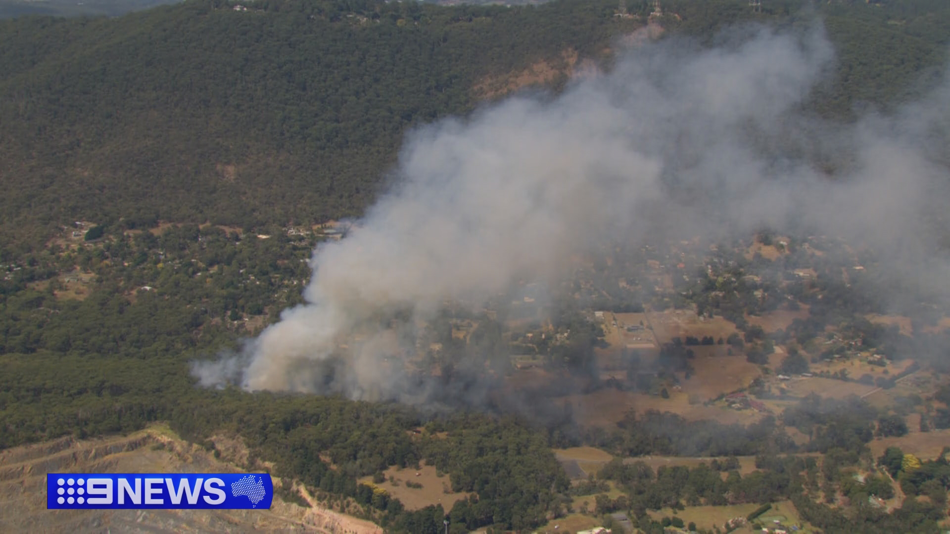 An out-of-control bushfire is burning dangerously close to homes in Melbourne's east as erratic winds and heatwave conditions are felt across the city.