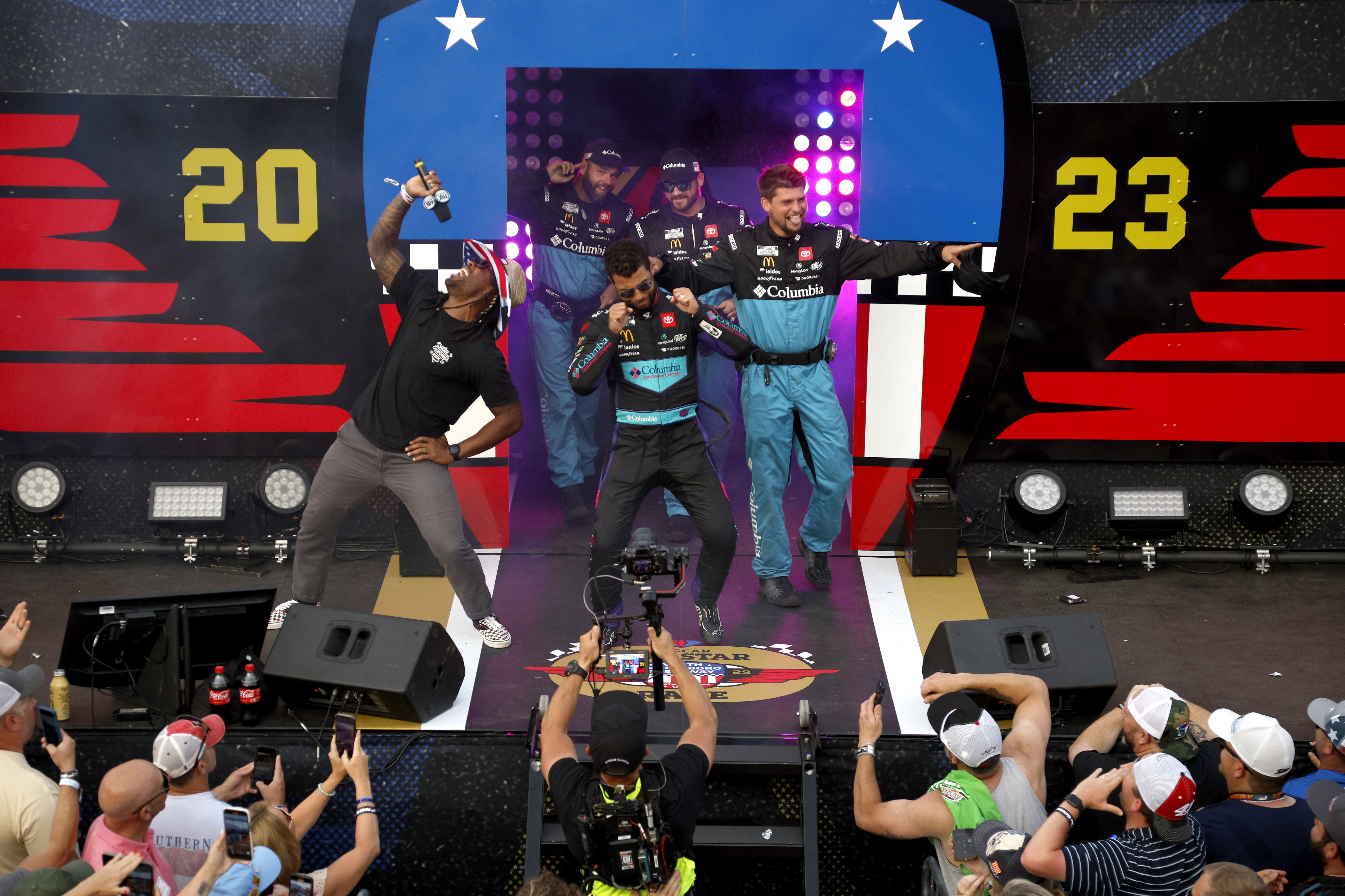 Bubba Wallace walks onstage during driver intros prior to the NASCAR Cup Series All-Star Race at North Wilkesboro Speedway, seemingly mocking fans.