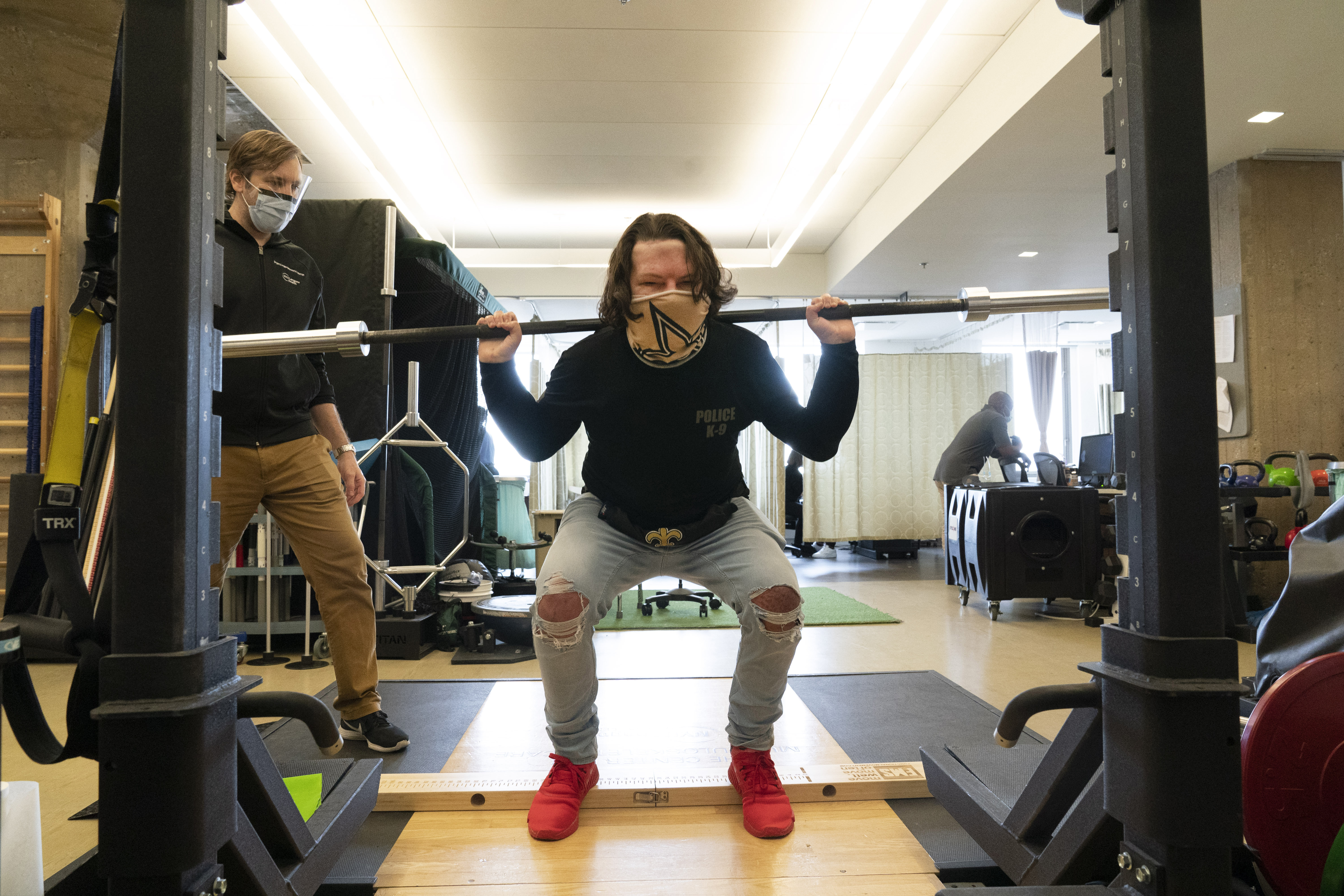 Physical therapist Eric Ross, left, watches as Joe DiMeo lifts weights, Monday, Jan. 25, 2021 at NYU Langone Health in New York. (AP Photo/Mark Lennihan)