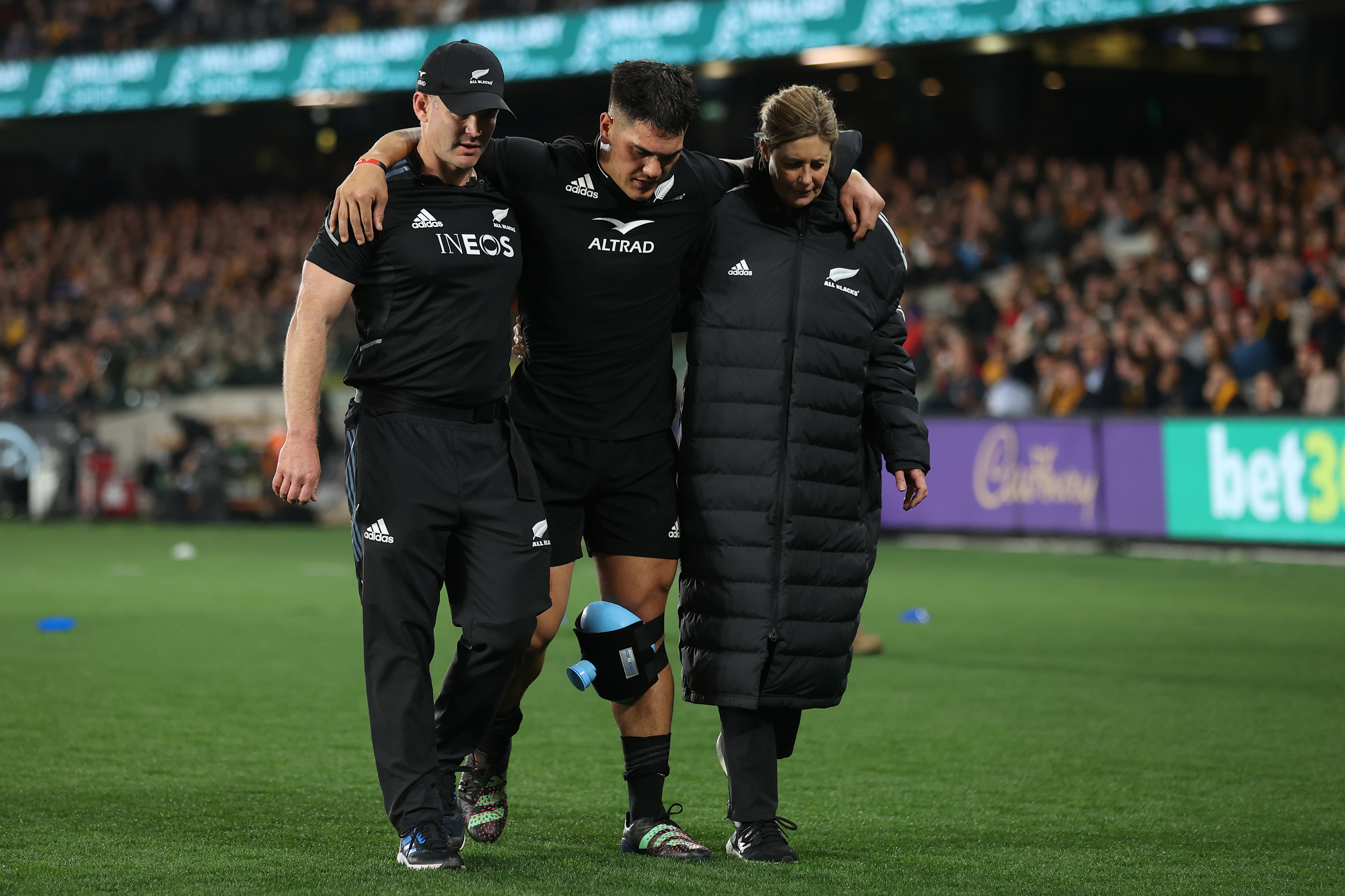 Quinn Tupaea wanders from the field with assistance after suffering a busted MCL and torn ACL.