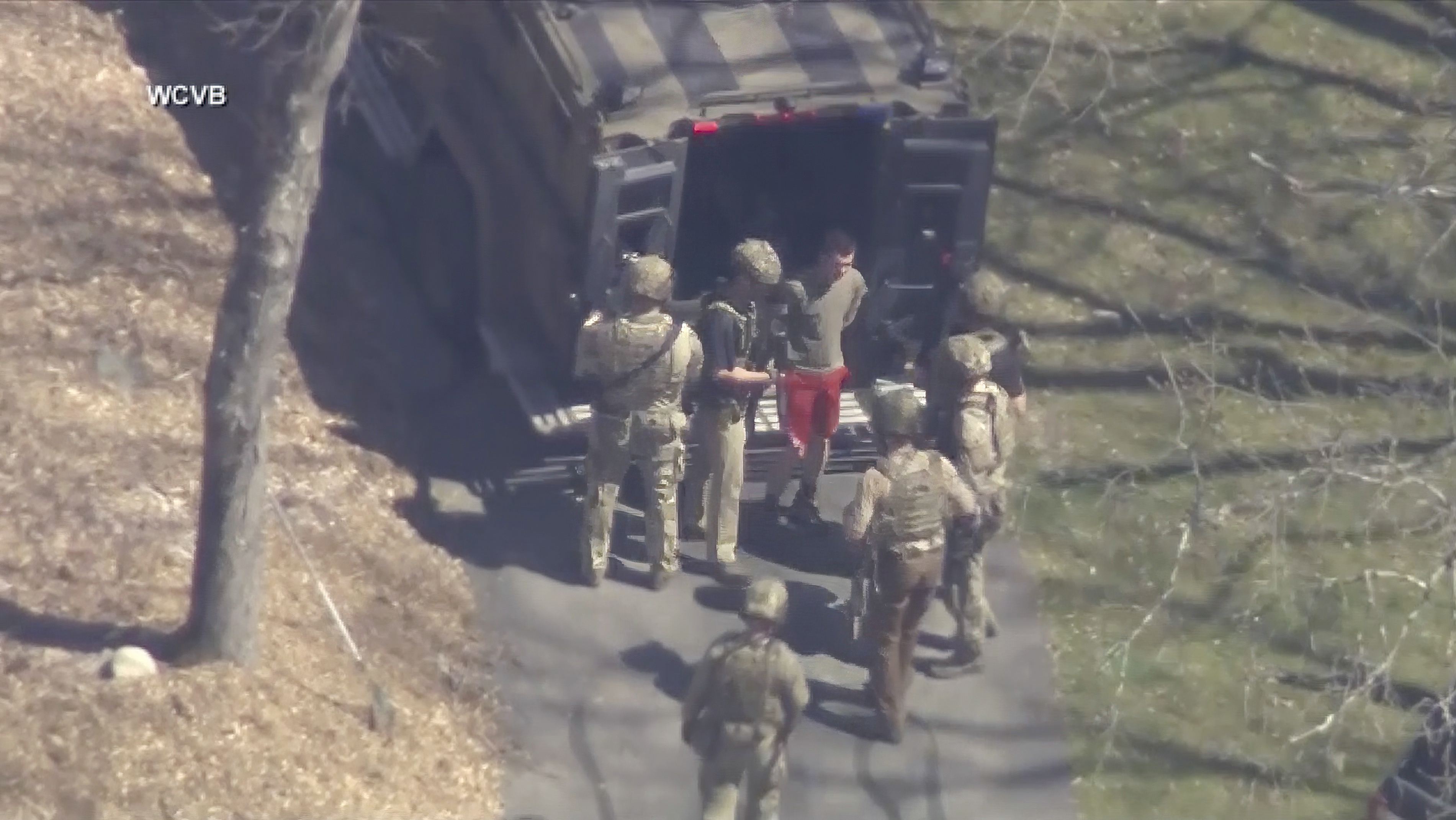 Esta imagen tomada de un video proporcionado por WCVB-TV muestra a Jack Teixeira, en camiseta y pantalones cortos, siendo detenido por agentes tácticos armados el jueves 13 de abril de 2023 en Dighton, Massachusetts.
