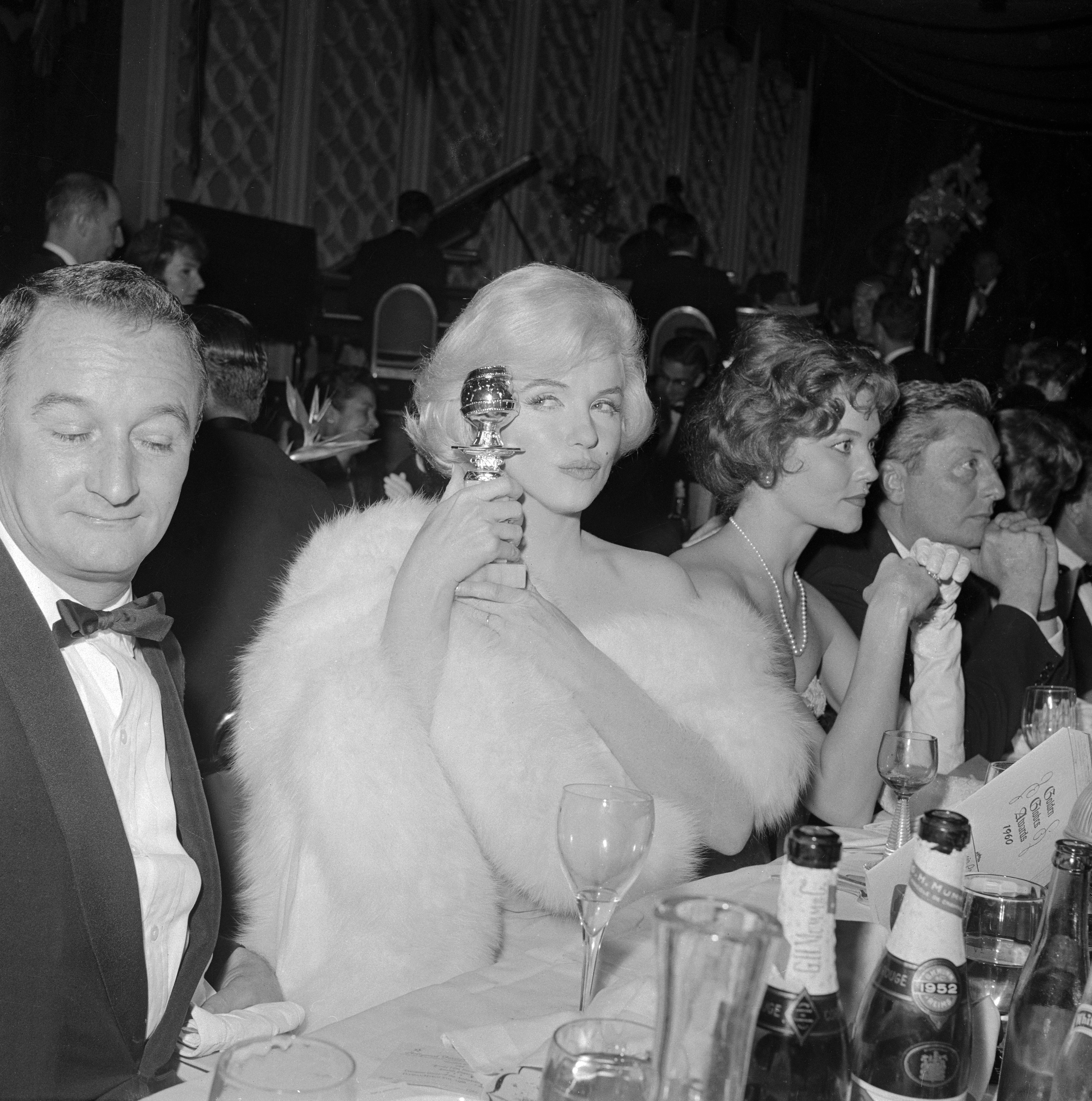 Marilyn Monroe eyes her Golden Globe award for Best Actress at the awards ceremony in 1960