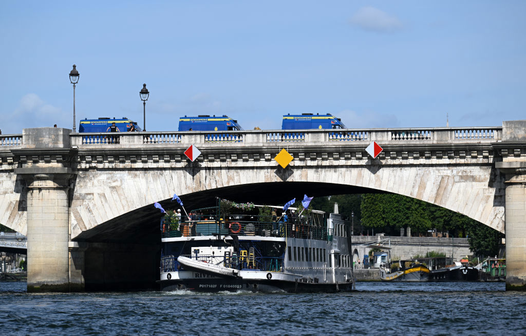 A test event for the Paris 2024 opening ceremony on the Seine while police guard the bridge.