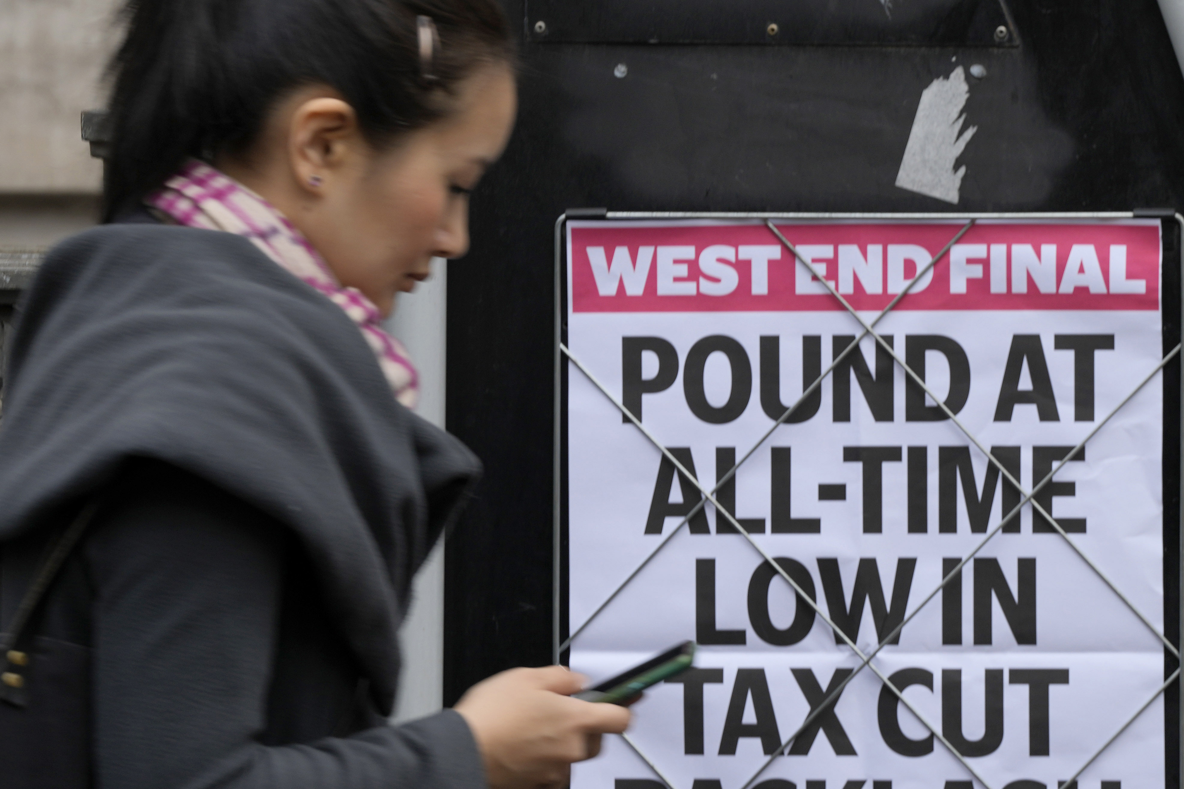 Una mujer pasa frente a un titular publicado en una pared en Londres, el martes 27 de septiembre de 2022. 