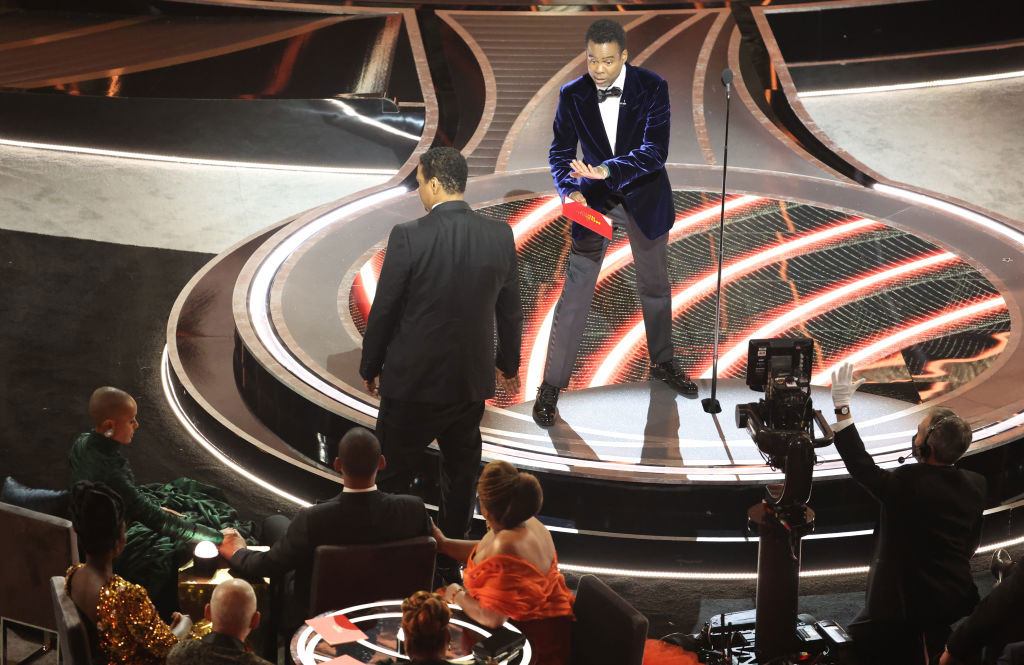 Denzel Washington talks to Chris Rock  onstage after the presenter was struck by Will Smith.