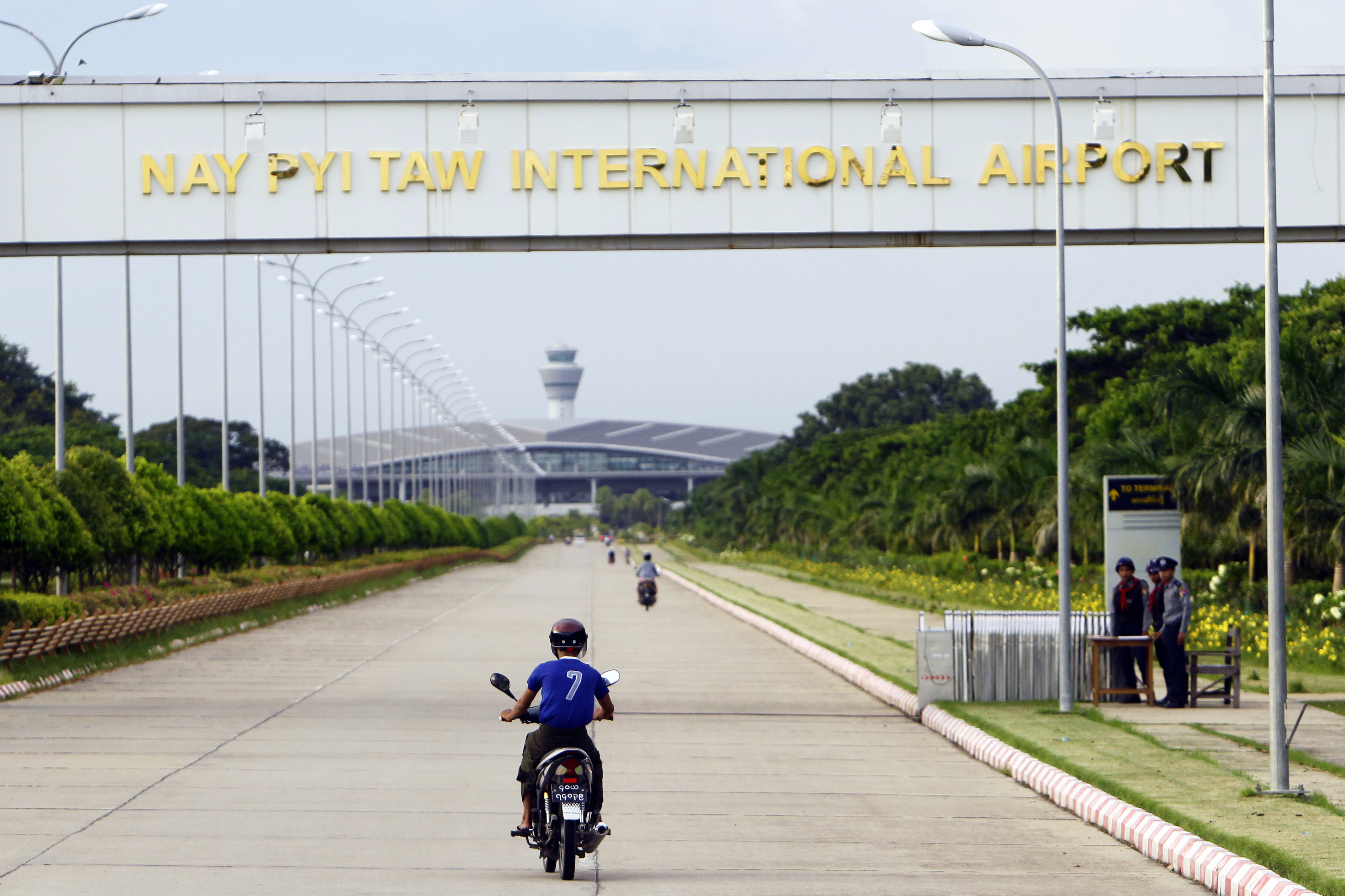 A resident drives motorbike to Naypyitaw International Airport as security police stand guard, Thursday, Sept. 29, 2016, in Naypyitaw, Myanmar.