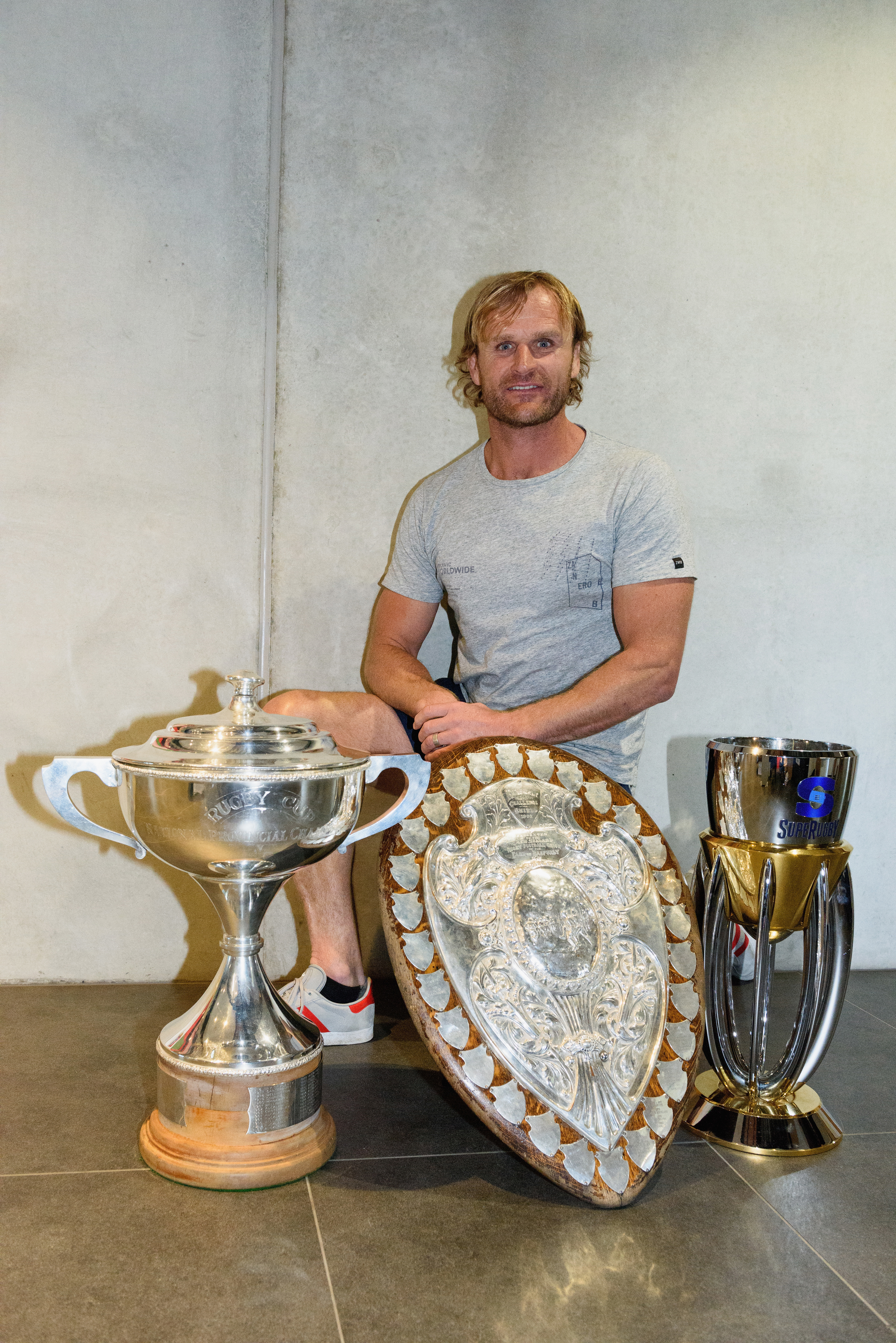 Scott Robertson poses with the Mitre 10 Cup, the Ranfurly Shield and the Super Rugby trophy in 2017.
