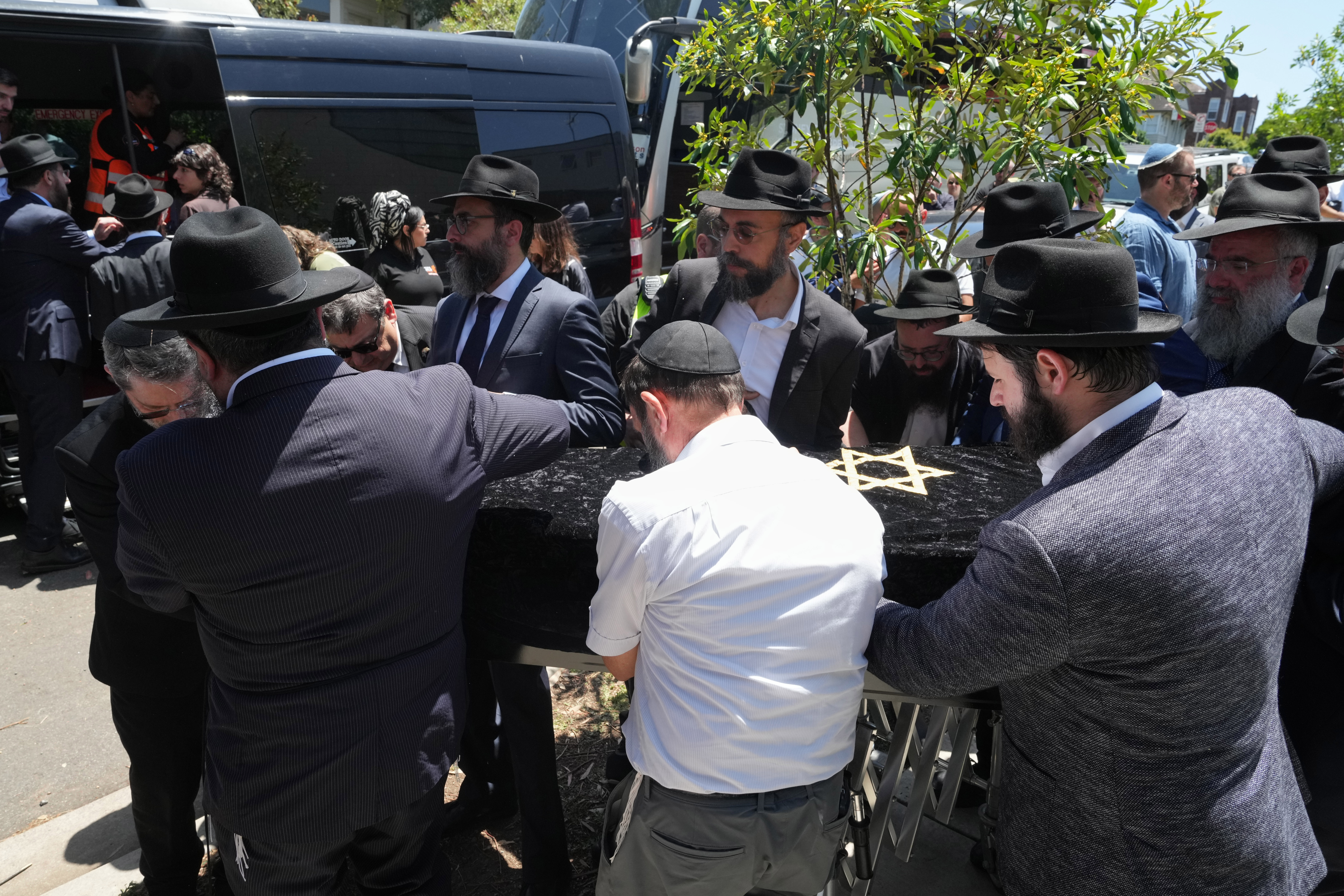 The coffin of Rabbi Eli Schlanger, a victim in the Bondi Beach mass shooting, is escorted out of a synagogue after his funeral service in Bondi on Wednesday, Dec. 17, 2025, in Sydney, Australia. (AP Photo/Mark Baker, Pool)