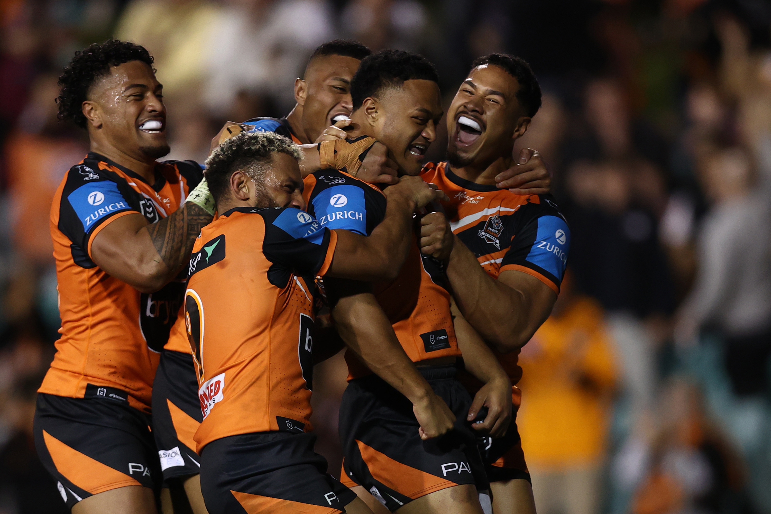 Latu Fainu of the Wests Tigers celebrates with teammates after scoring a try.