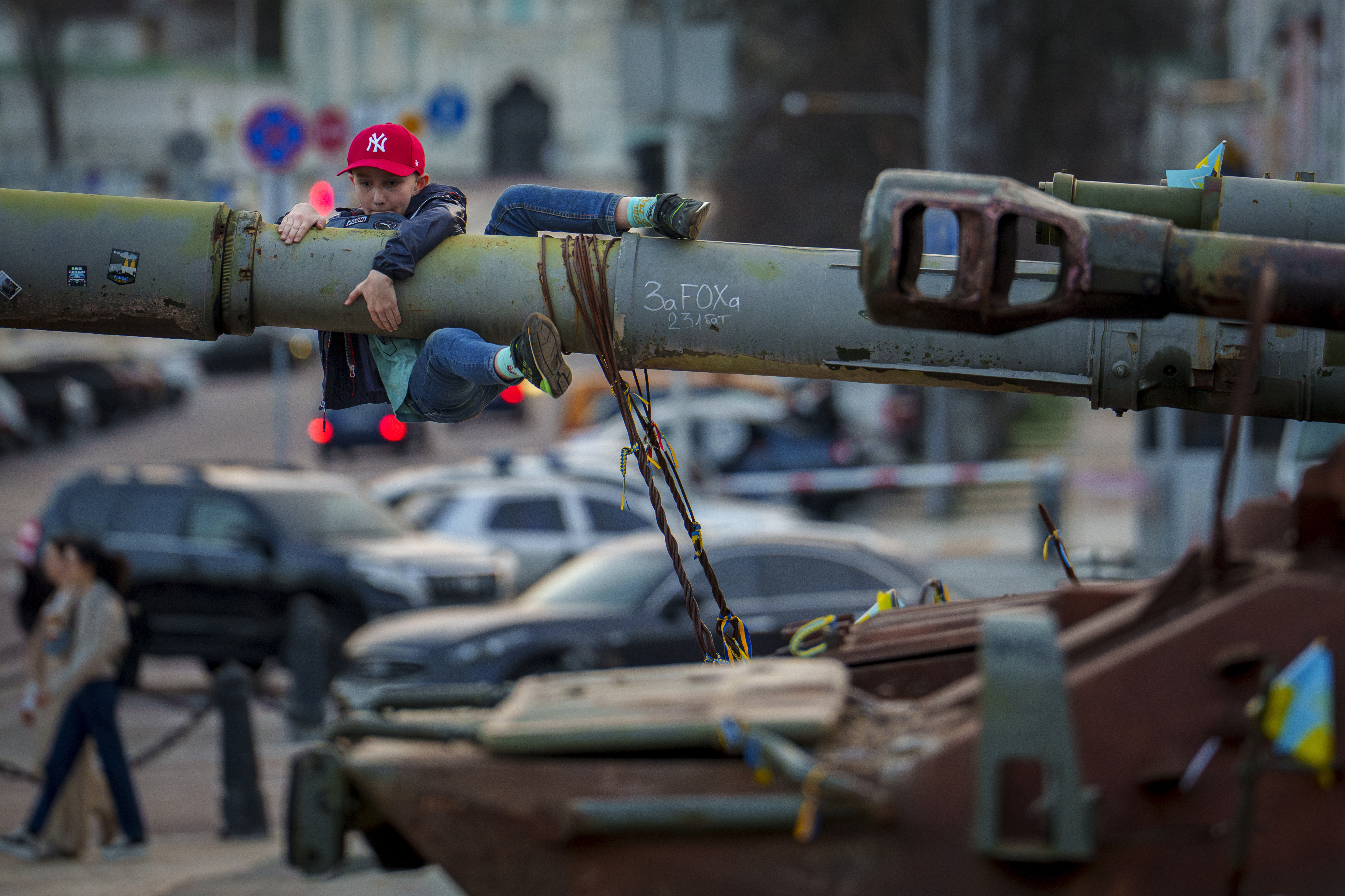 Un niño sostiene el cañón de un tanque, parte de una exhibición de equipo militar ruso destruido, en Kiev, Ucrania, el domingo 31 de marzo de 2024.
