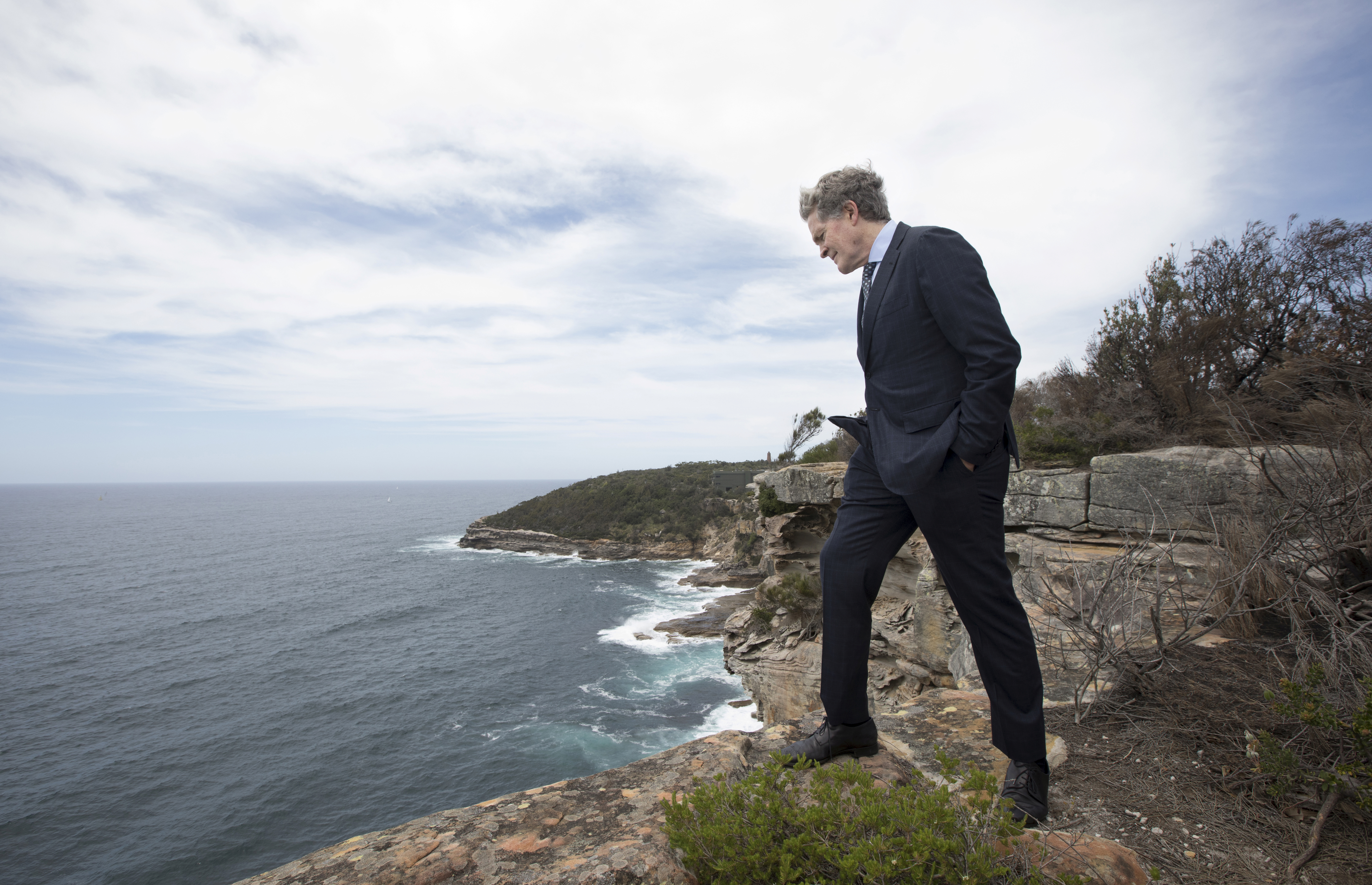 Steve Johnson, the brother of murdered Scott Johnson, looks down to the rocks and ocean below at the point along the cliff at Blue Fish Point, North Head, Manly where his brother fell to his death 30 years ago.