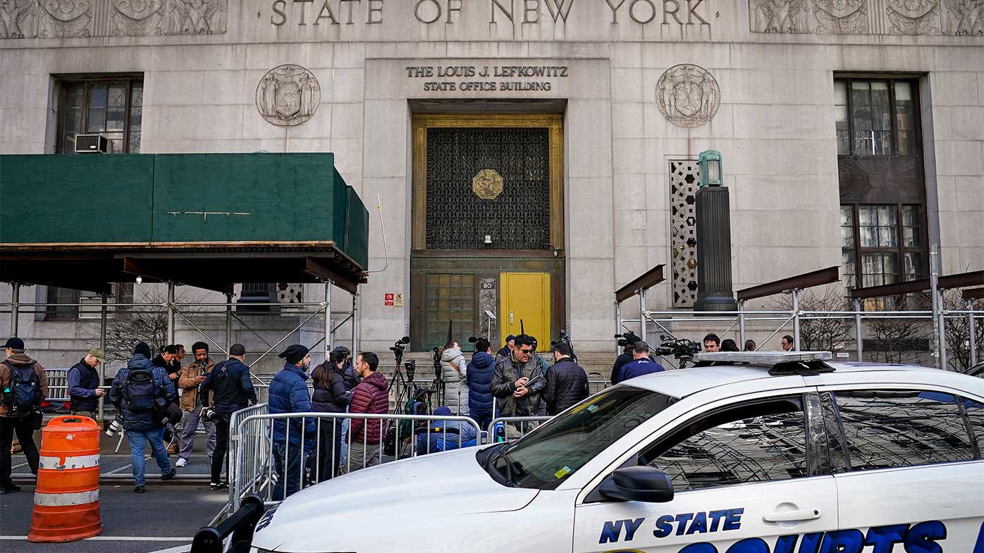 Los periodistas se reúnen frente a la entrada pública de un edificio de Nueva York donde se reunió un gran jurado para considerar los cargos contra Donald Trump.