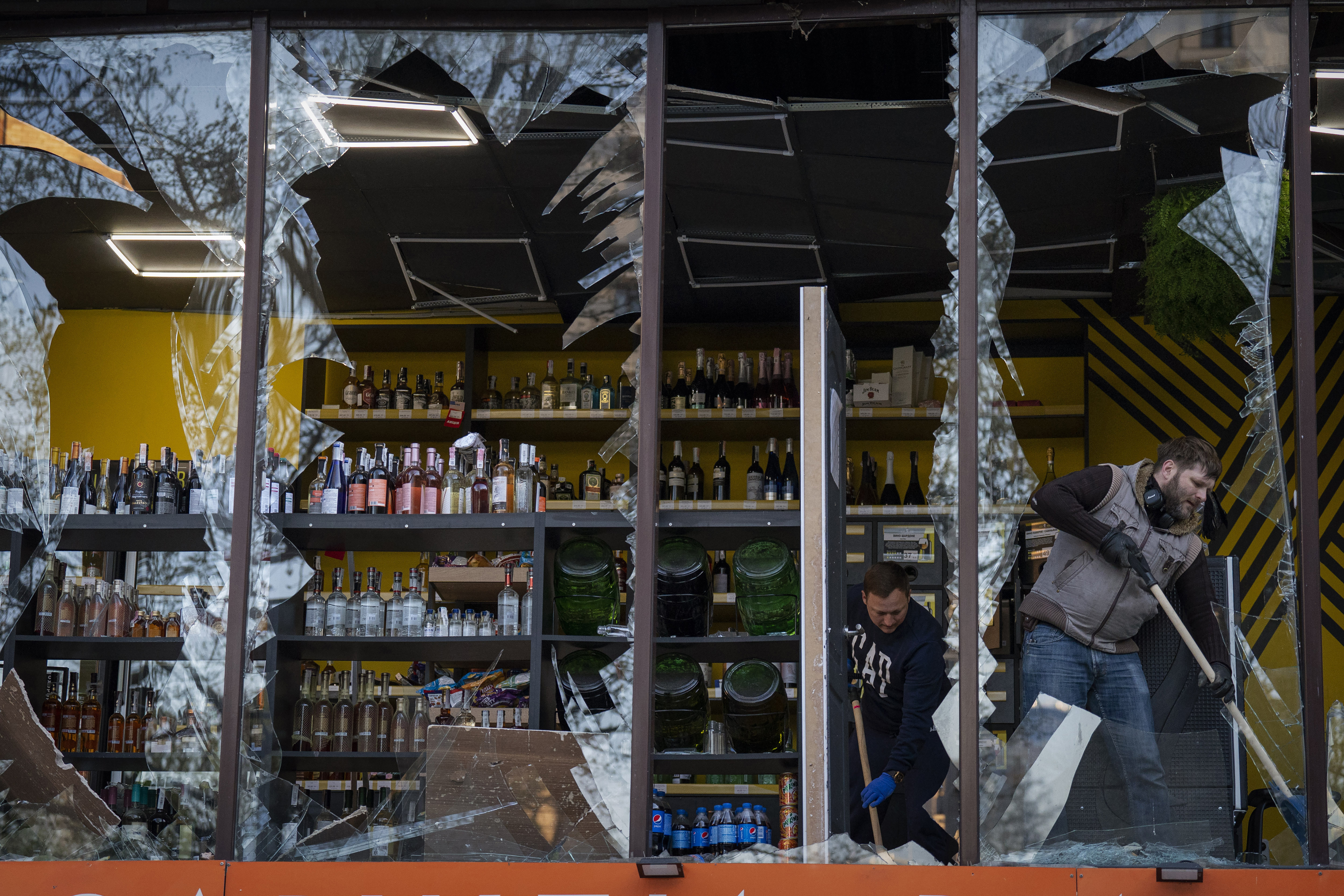 Employees at a liquor store clean the glasses broken during an explosion in Kyiv, Ukraine on Friday, April 29, 2022. Russia struck the Ukrainian capital of Kyiv shortly after a meeting between President Volodymyr Zelenskyy and U.N. Secretary-General António Guterres on Thursday evening. (AP Photo/Emilio Morenatti)