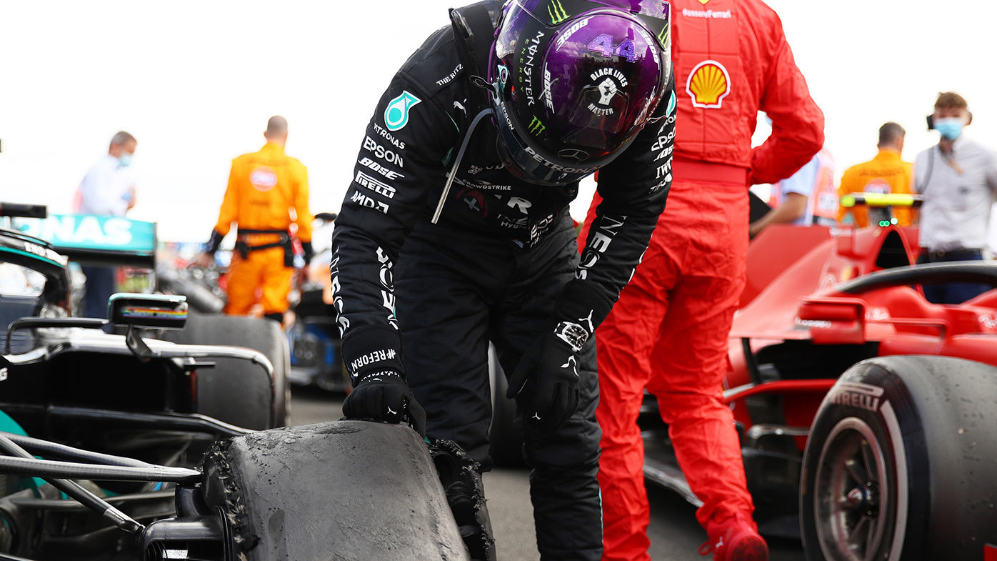 Lewis Hamilton inspects the remains of his left front tyre after the British Grand Prix.