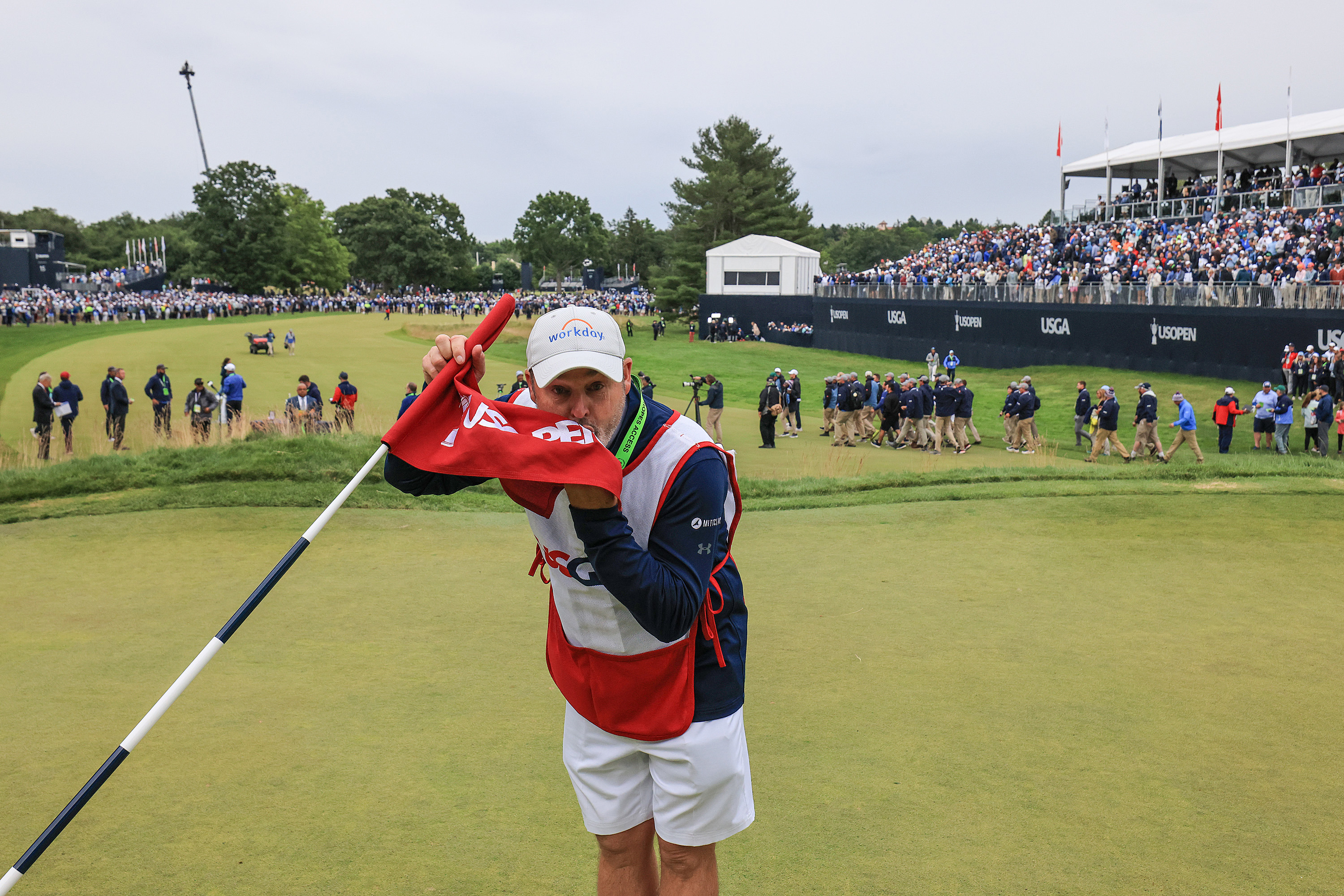 Billy Foster the caddie of US Open champion Matthew Fitzpatrick kisses the flag on the 18th green after Fitzpatrick's one shot victory.