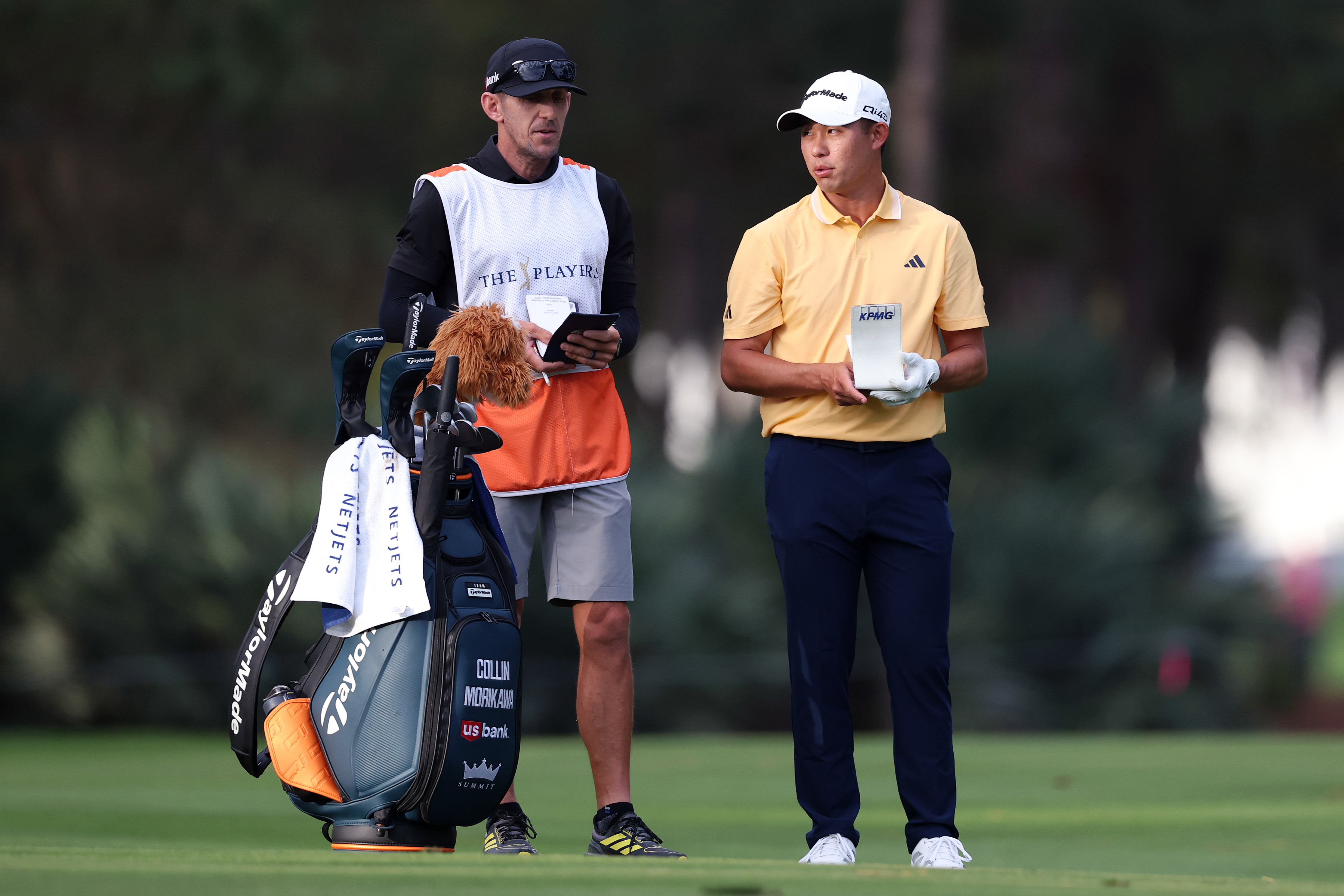 Collin Morikawa of the United States prepares for a shot with his caddie, Mark Urbanek, on the tenth hole during the first round of THE PLAYERS Championship.