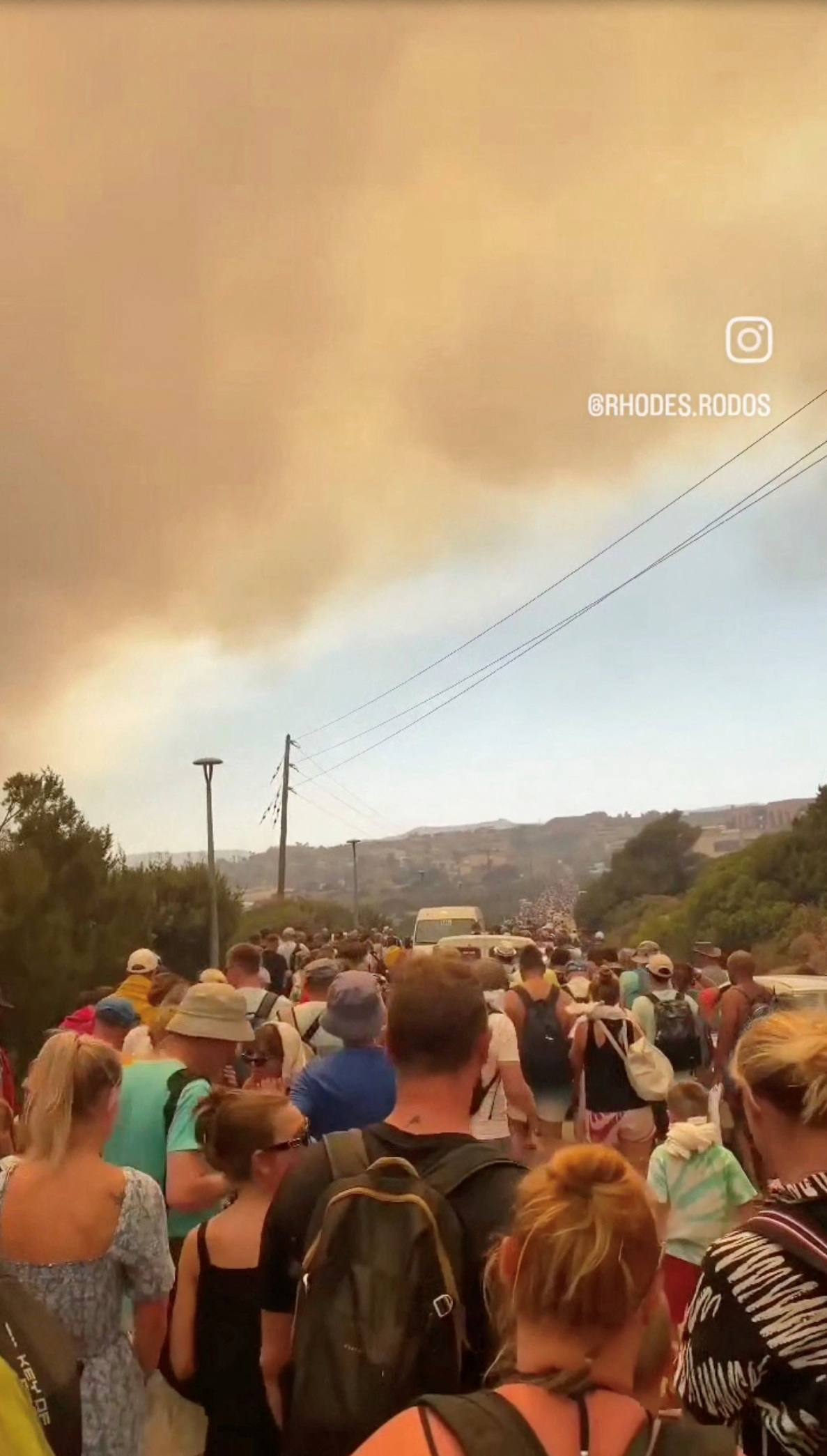 Crowds wait to be evacuated as wildfires burn in this video screengrab obtained from social media, in Rhodes, Greece, July 22, 2023.