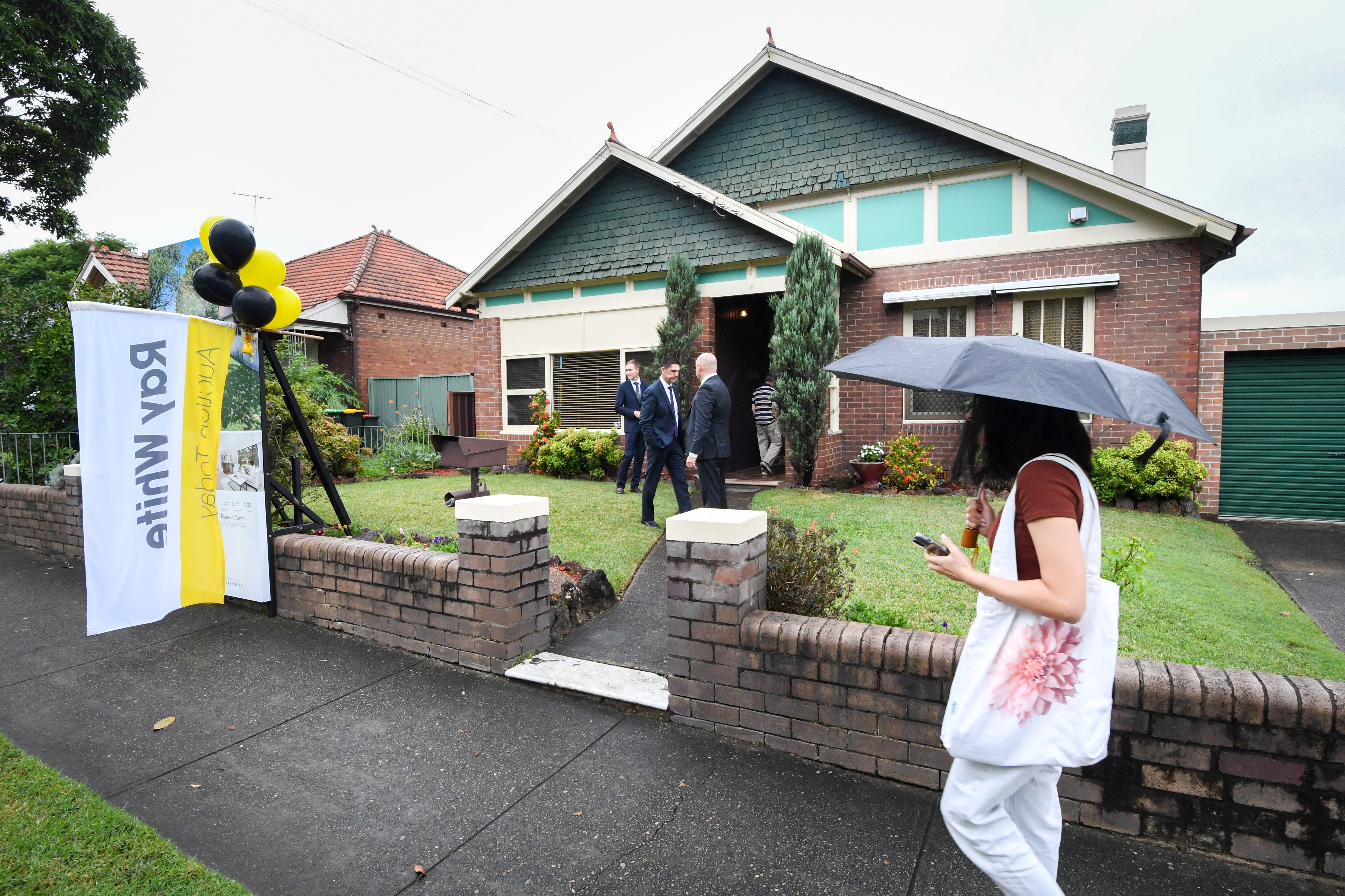 Someone with an umbrella walks past an auction.