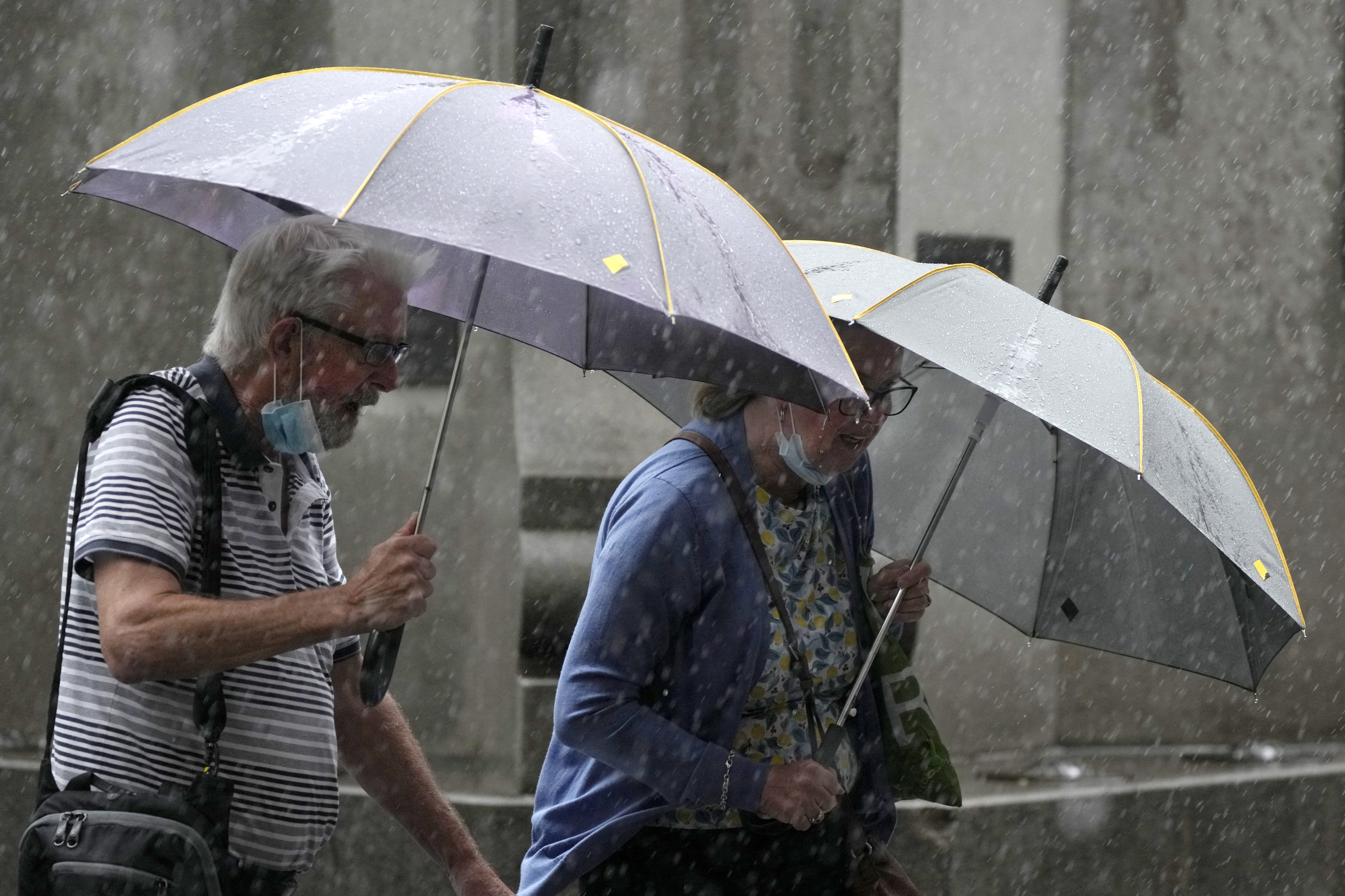 Pedestrians use umbrellas to shield the rain in Sydney, Wednesday, March 2, 2022, as parts of Australia's southeast coast were inundated by the worst flooding in more than a decade. Floodwaters are moving south into New 