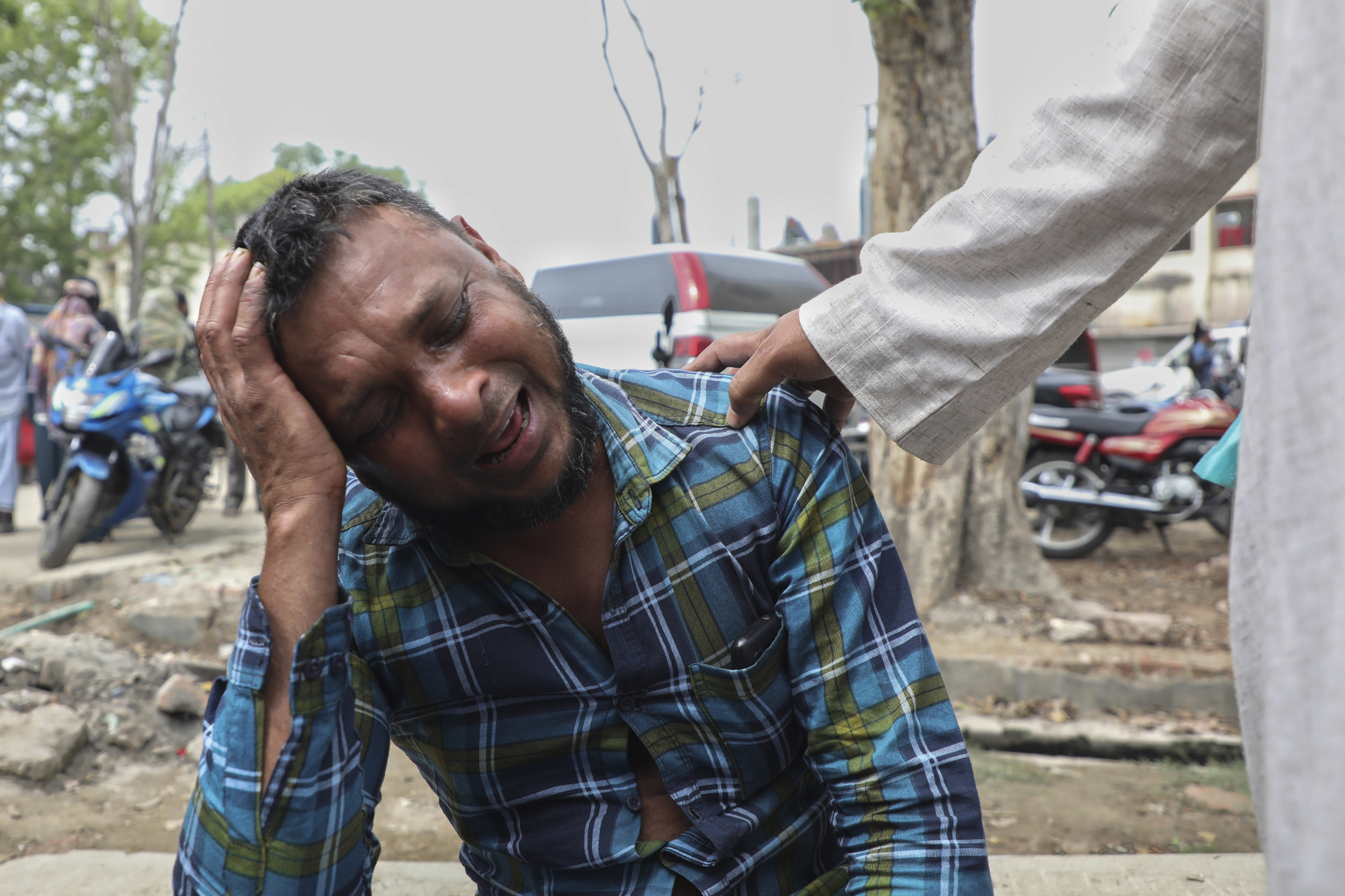 An unidentified man grieves as relatives receive bodies of victims of a road accident after a bus fell into a roadside ditch in Shibchar area in Madaripur district, Bangladesh, Sunday, March 19, 2023.