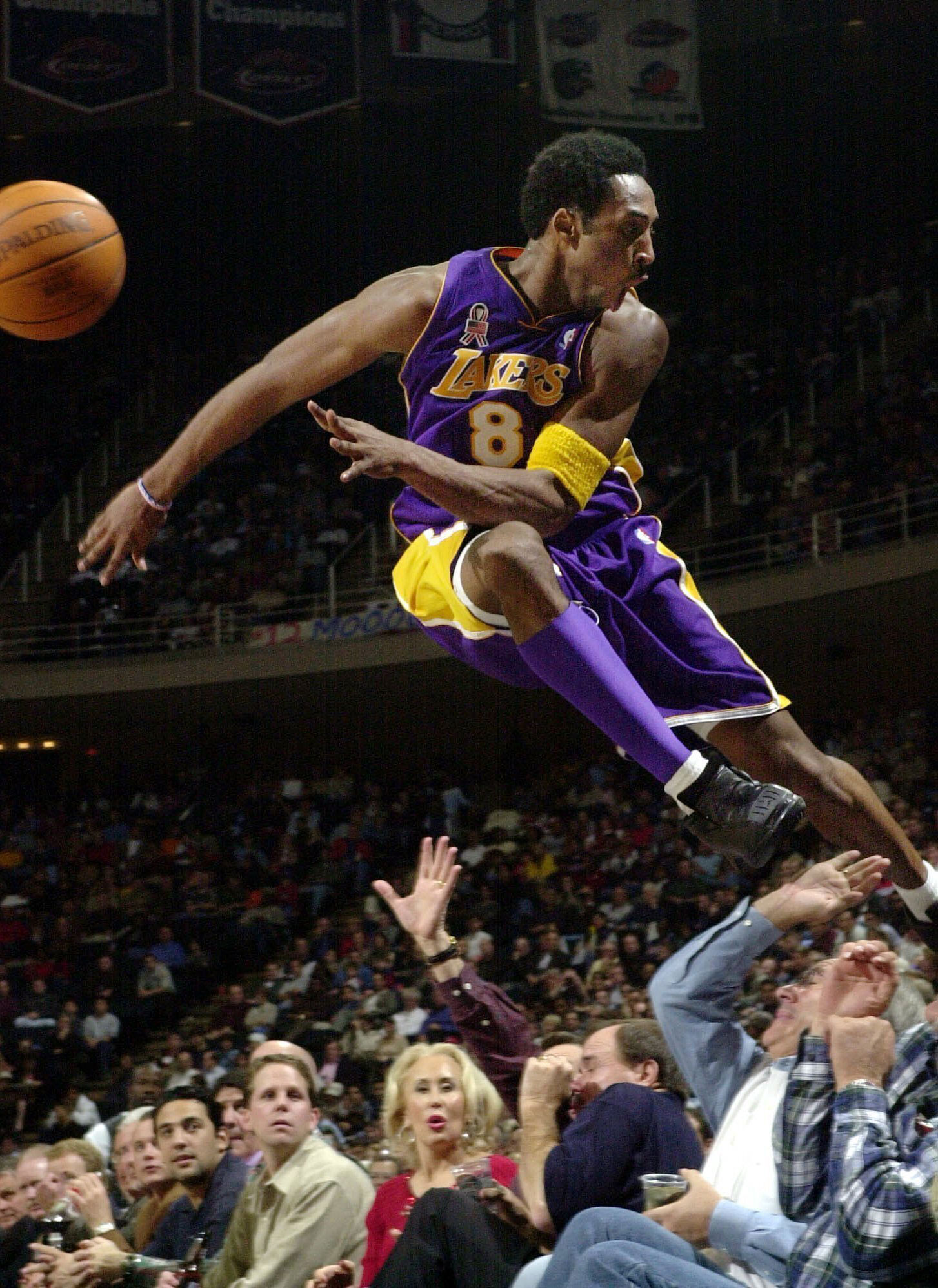 In this 2001 photo Los Angeles Lakers' Kobe Bryant jumps over a row of fans after saving the ball from going out of bounds.