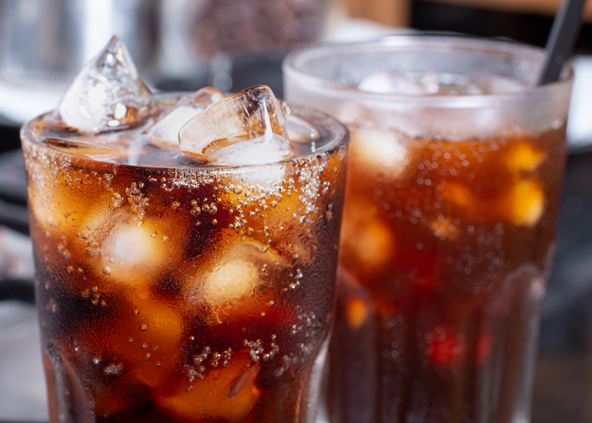 cola con hielo picado en un vaso y hay gotas de agua alrededor.  bebida fresca y negra.