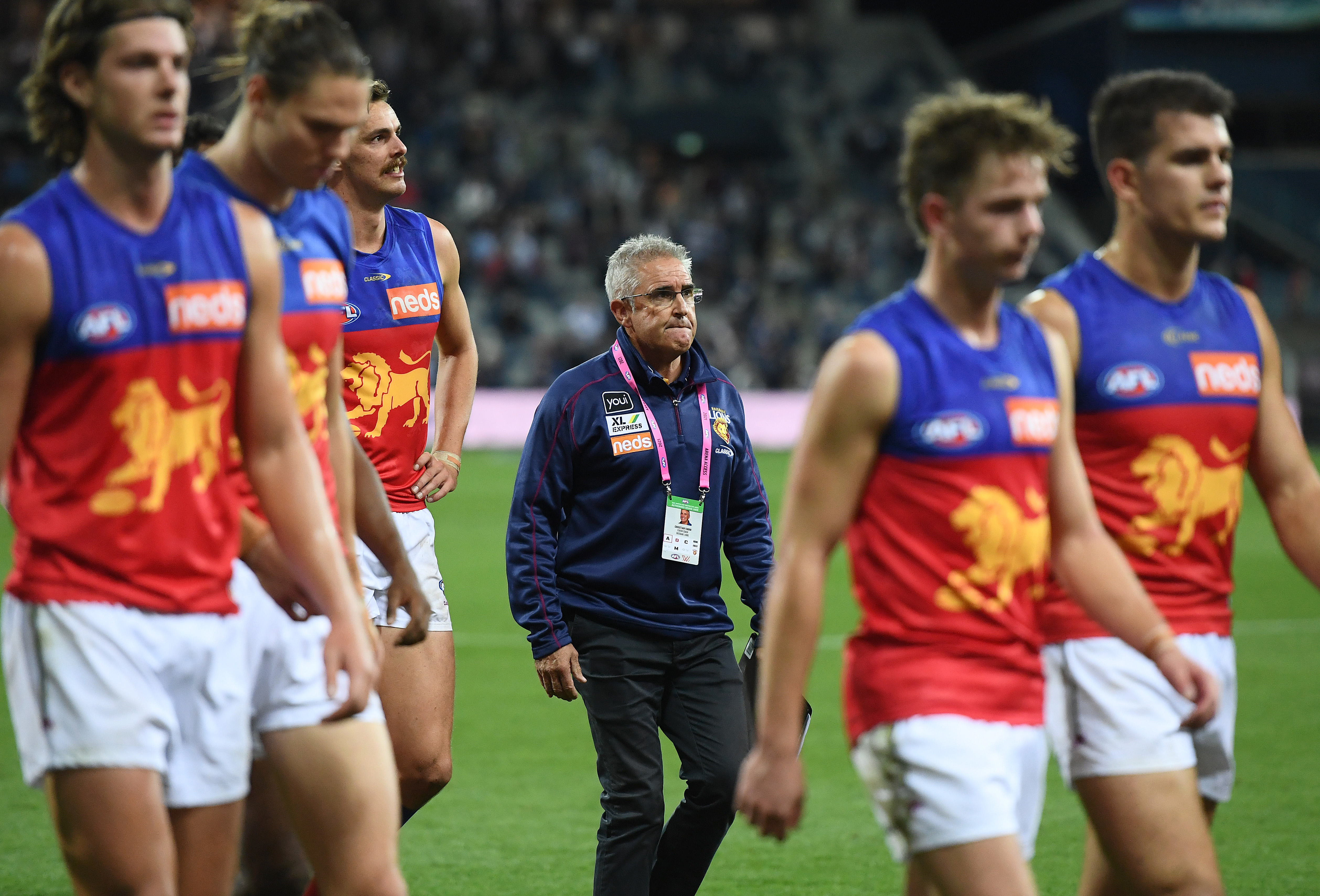 Chris Fagan the coach of the Lions and his team mates look dejected as they walk off the field after losing the round 2 AFL match between the Geelong Cats and the Brisbane Lions at GMHBA Stadium on March 26, 2021 in Geelong, Australia.