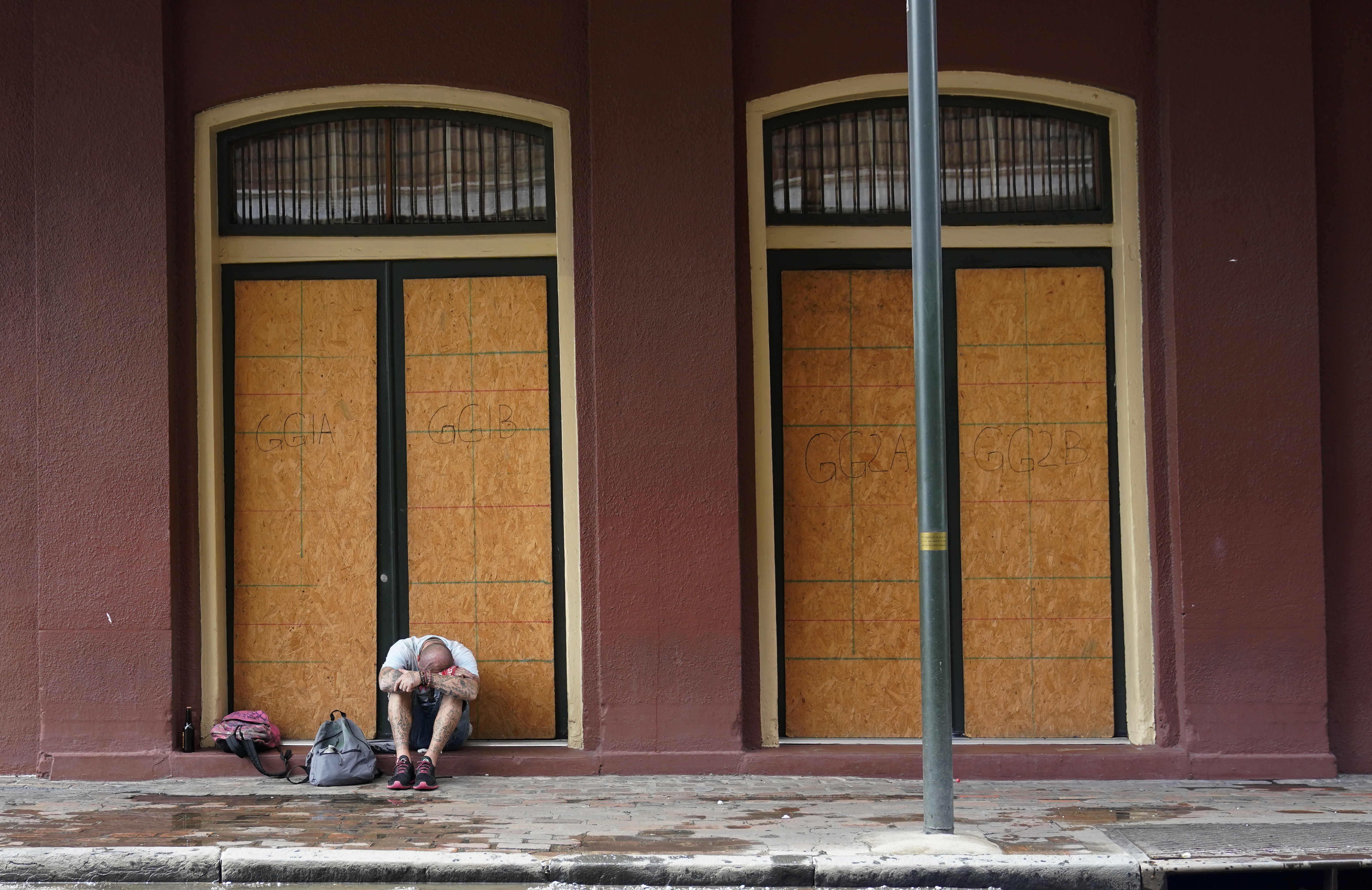 A man sits in front of a French Quarter business with windows boarded in preparation Hurricane Ida. (AP Photo/Eric Gay)