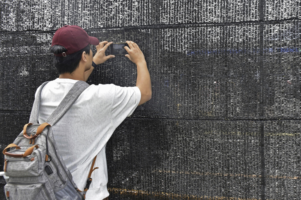 A visitor tries to take a photo through a hole on a black screen in Fujikawaguchiko town