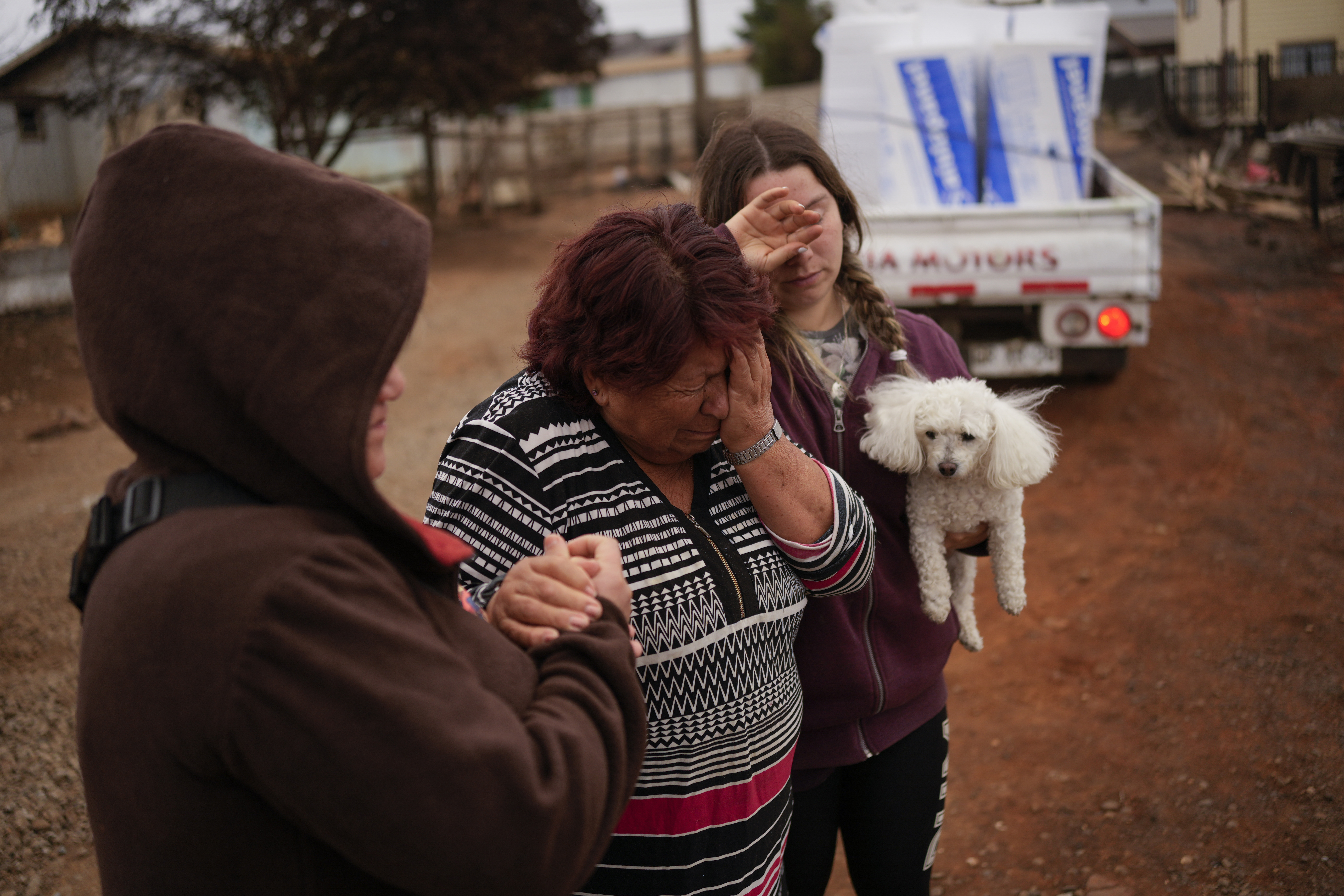 Rosa Munoz, centre, reacts after fires destroyed her house in Tome, Chile, Saturday, Feb. 4, 2023. 