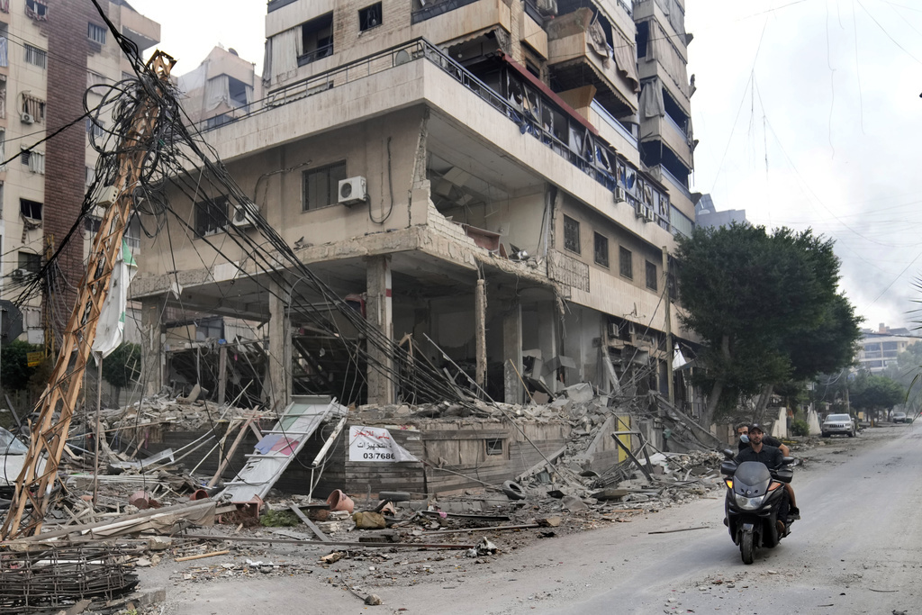 Lebanese men ride a scooter past a damaged building hit by an Israeli airstrike in Dahiyeh, Beirut, Lebanon, Monday, October 7, 2024