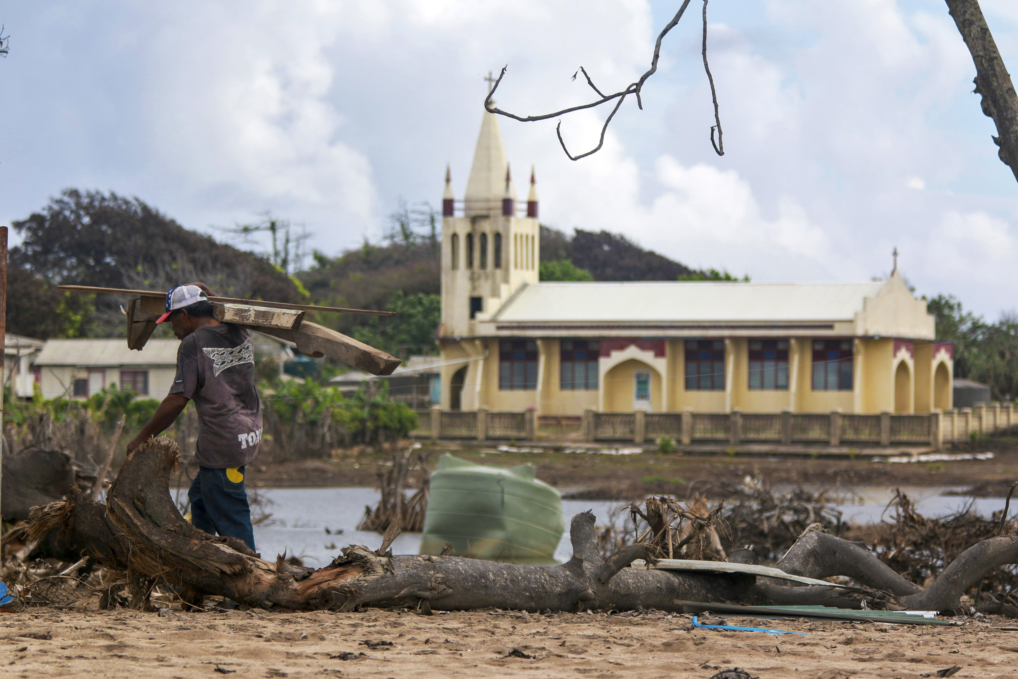 In this photo supplied by the Royal Australian Navy, a local man clears debris on Nomuka Island in Tonga Feb. 26, 2022. Three months on from a devastating volcano and tsunami in Tonga, the AP checks in on how the island nation is recovering. The bill from the tsunami is estimated at some $90 million and GDP is expected to fall by more than 7% this year. The cleanup has been hindered by an internet outage caused by the tsunami and the nations first outbreak of COVID-19. (LSCSO Rye Huckel/Royal Au